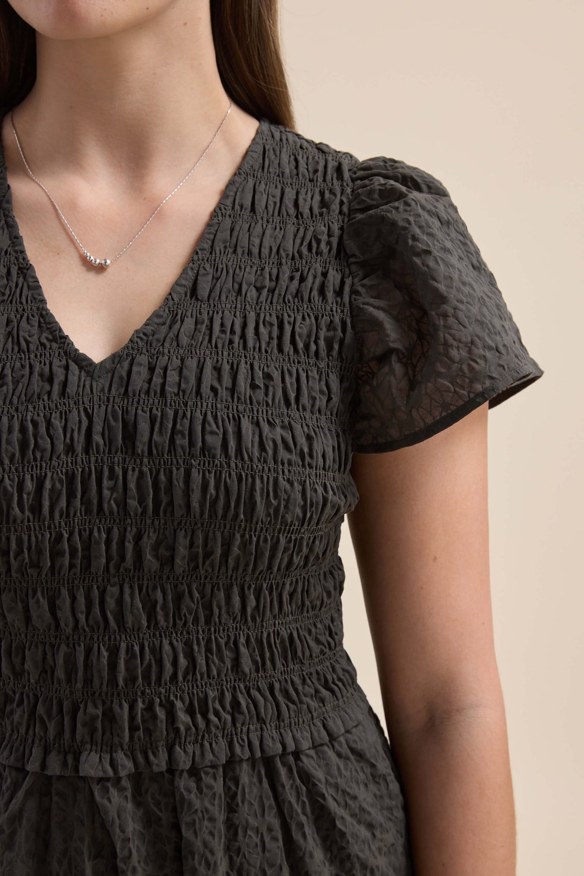 Woman in Elementary Shirred Bodice Dress with puff sleeves, plus a delicate silver necklace.