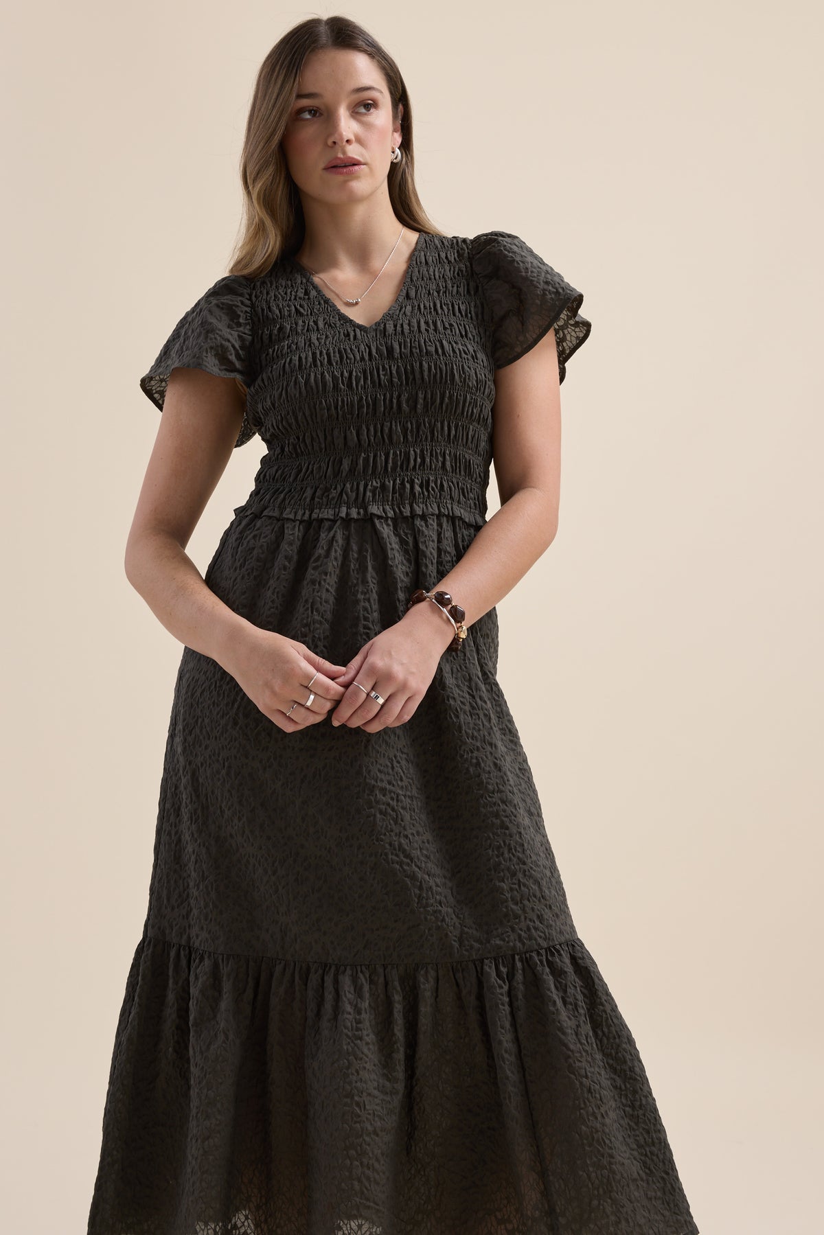 Woman in an Elementary Shirred Bodice Dress stands against a plain beige background.