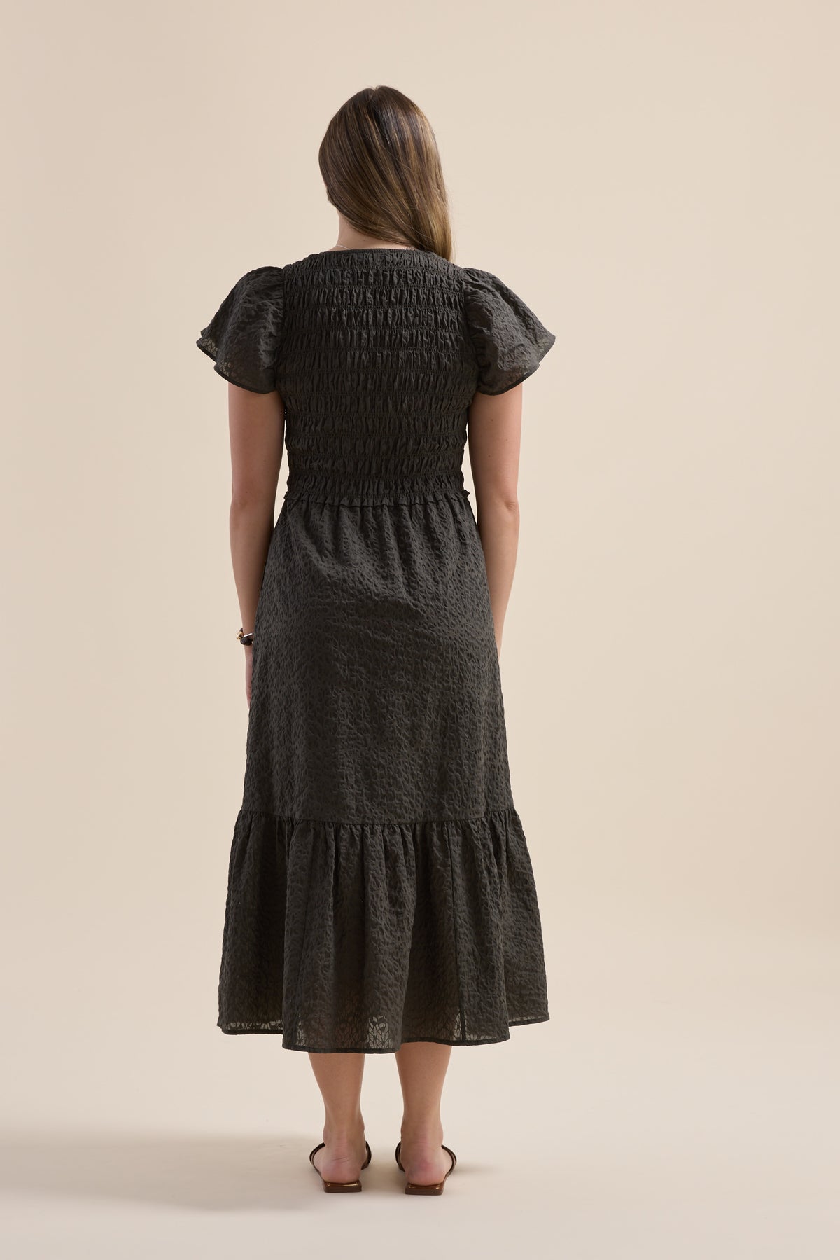 Woman in Elementary Shirred Bodice Dress, her back to the camera.