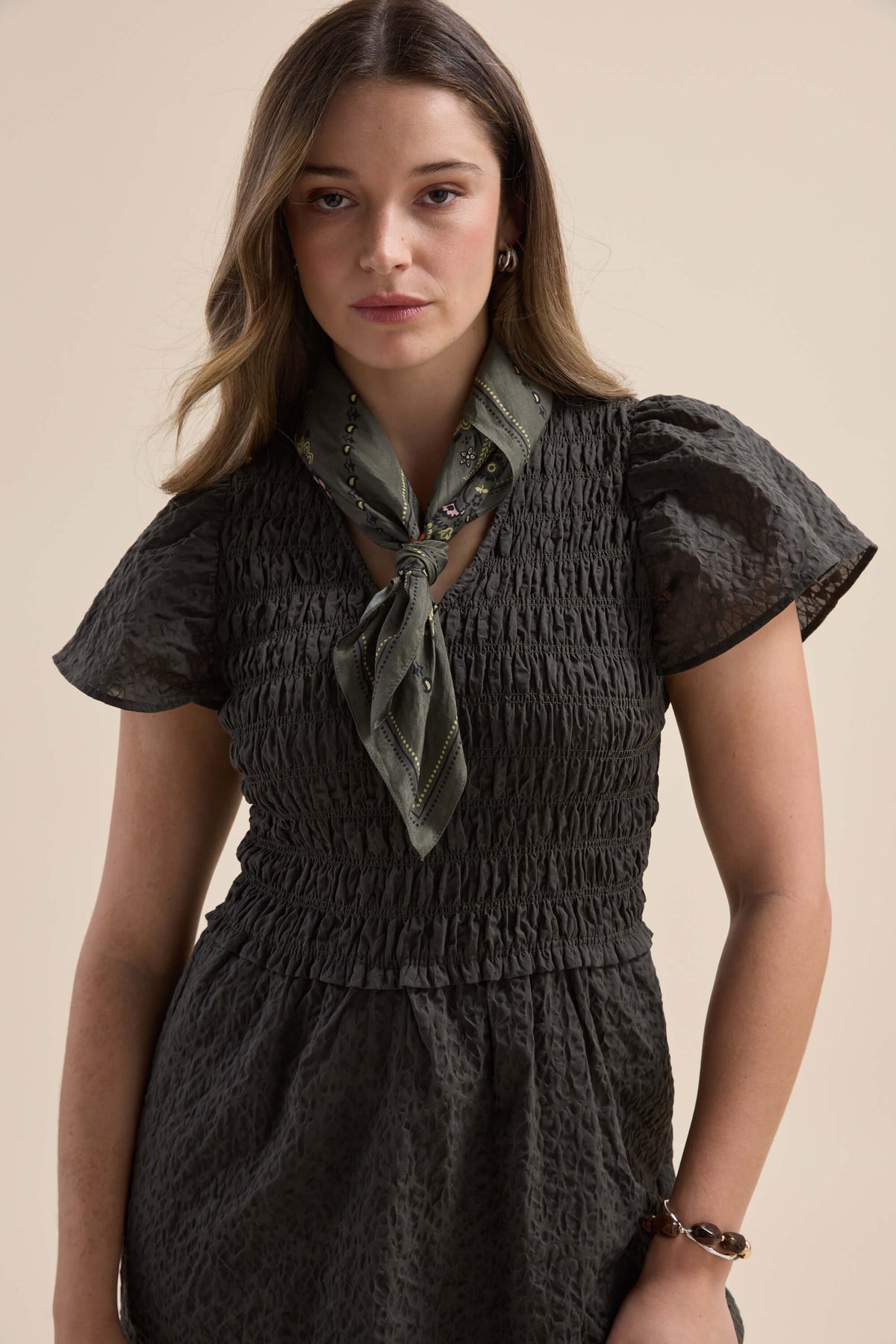 Woman in an Elementary Shirred Bodice Dress with short sleeves, styled with a green scarf.