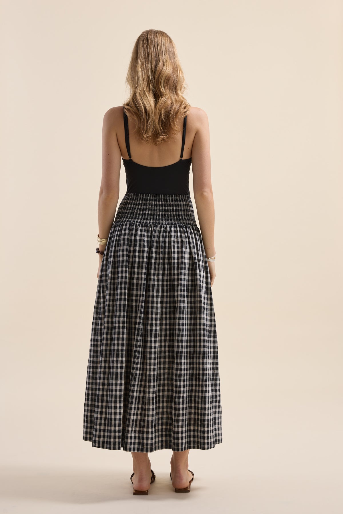Woman in a black tank and Elementary Shirred Drop Waist Skirt, back to camera.