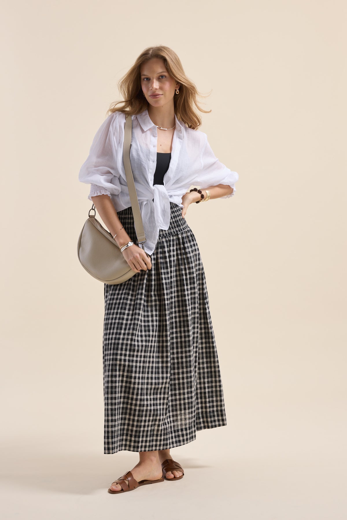 Woman in white blouse, Elementary Shirred Drop Waist Skirt, tan sandals, silver bag, confident.