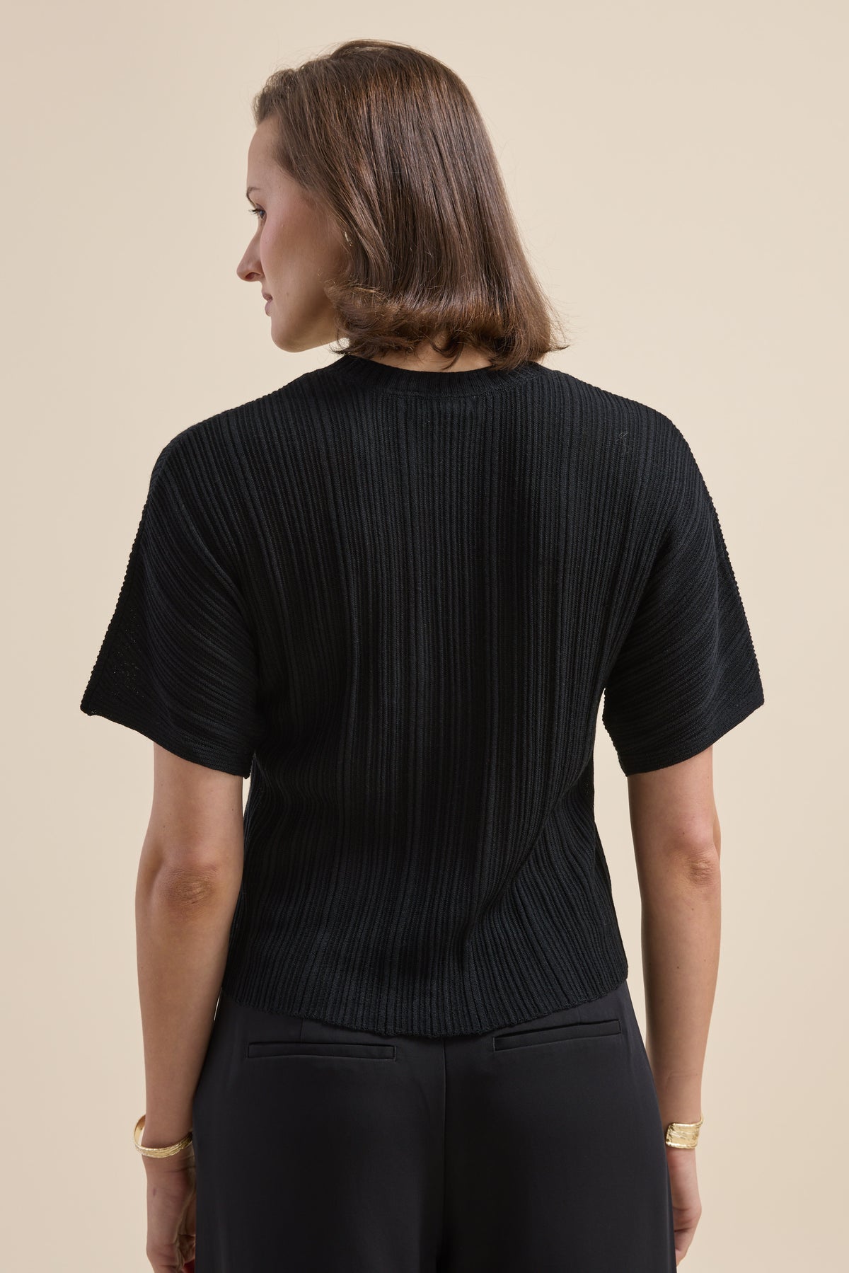 Woman in Max’s Merino Silk Knit Detail Tee and matching black pants, back turned.