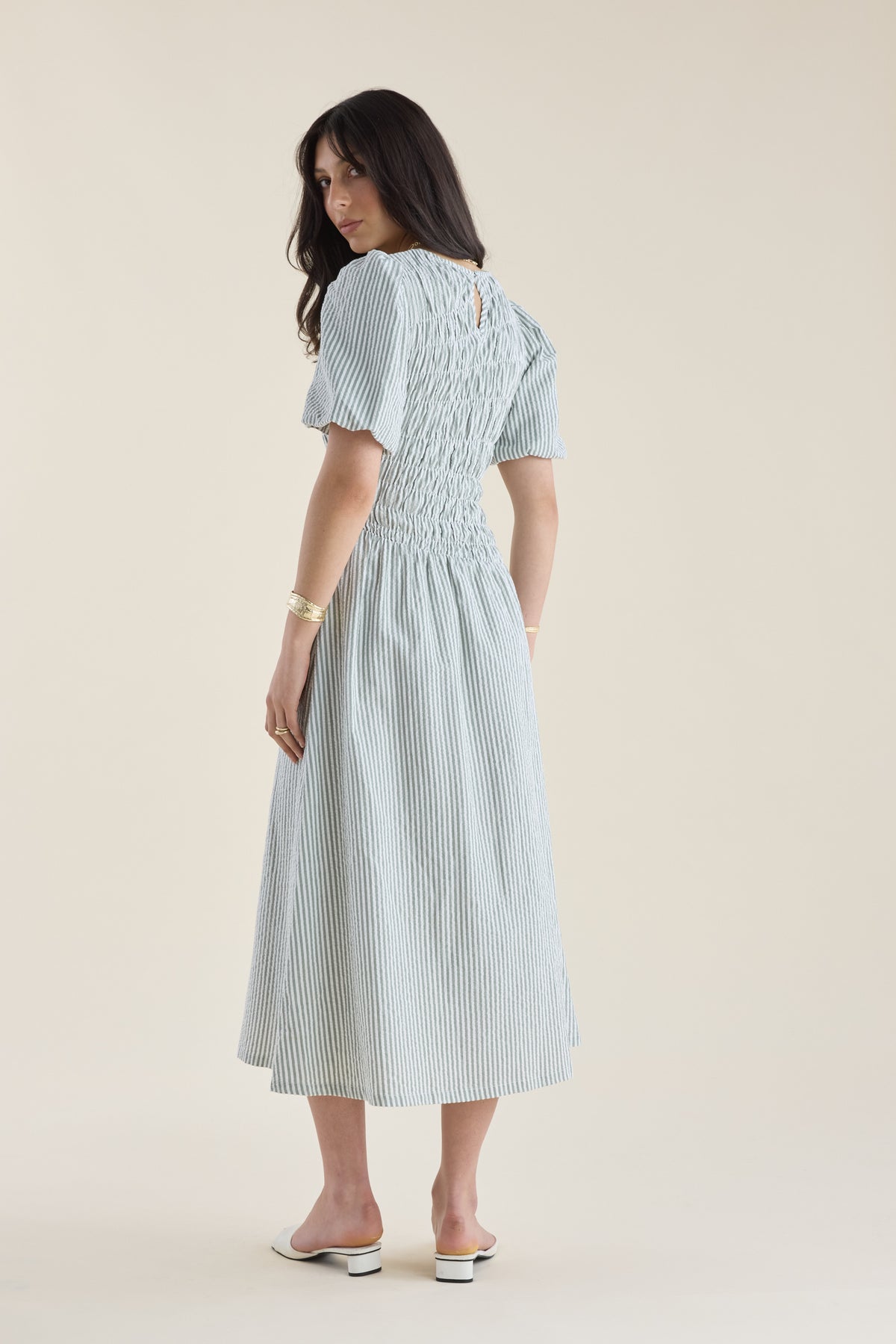 Woman in a Max Talia Shirred Detail Midi Dress with puff sleeves, looking over her shoulder.