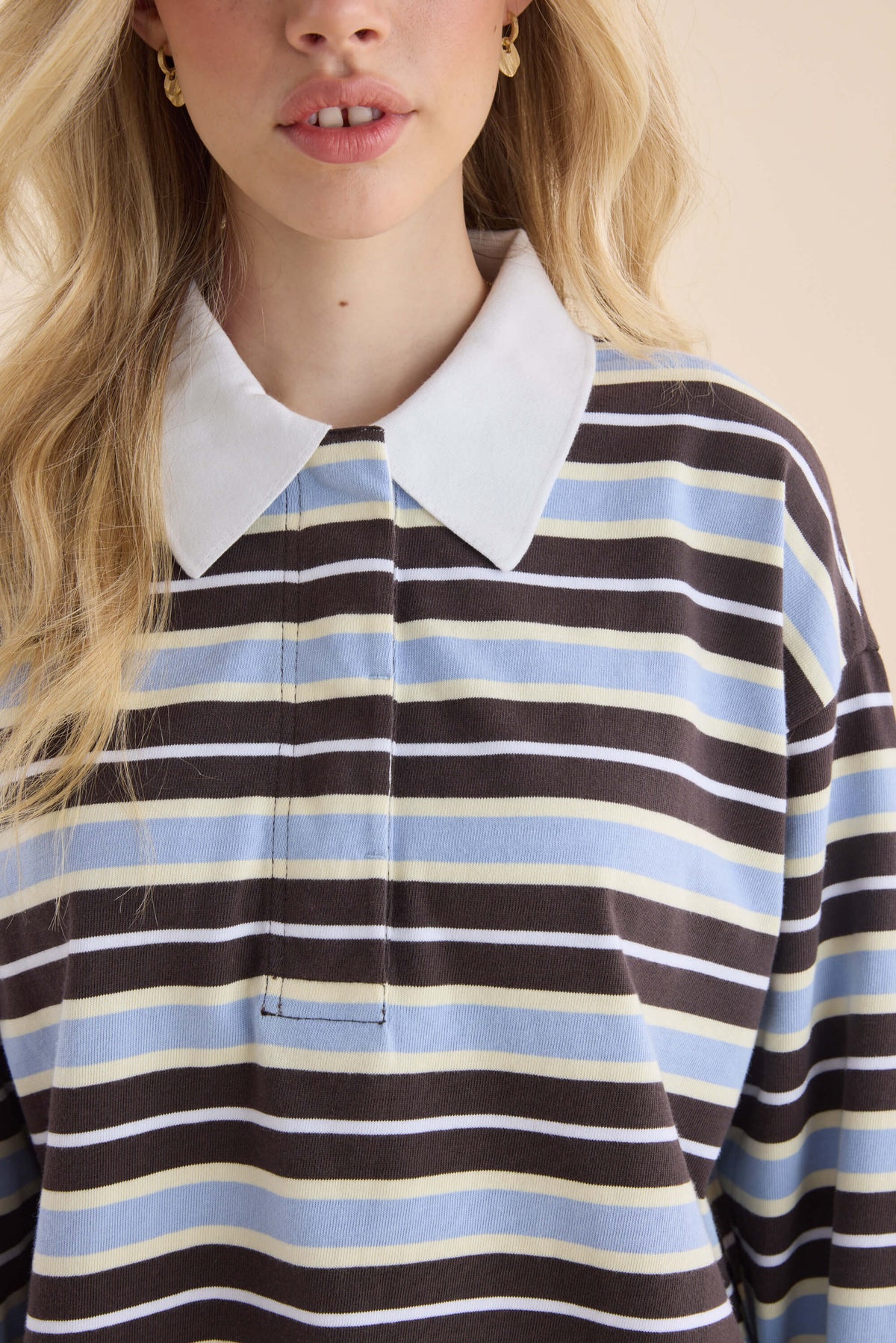 Woman in Elementary Ice Blue Stripe Polo Top, white collar, blonde hair, relaxed silhouette.