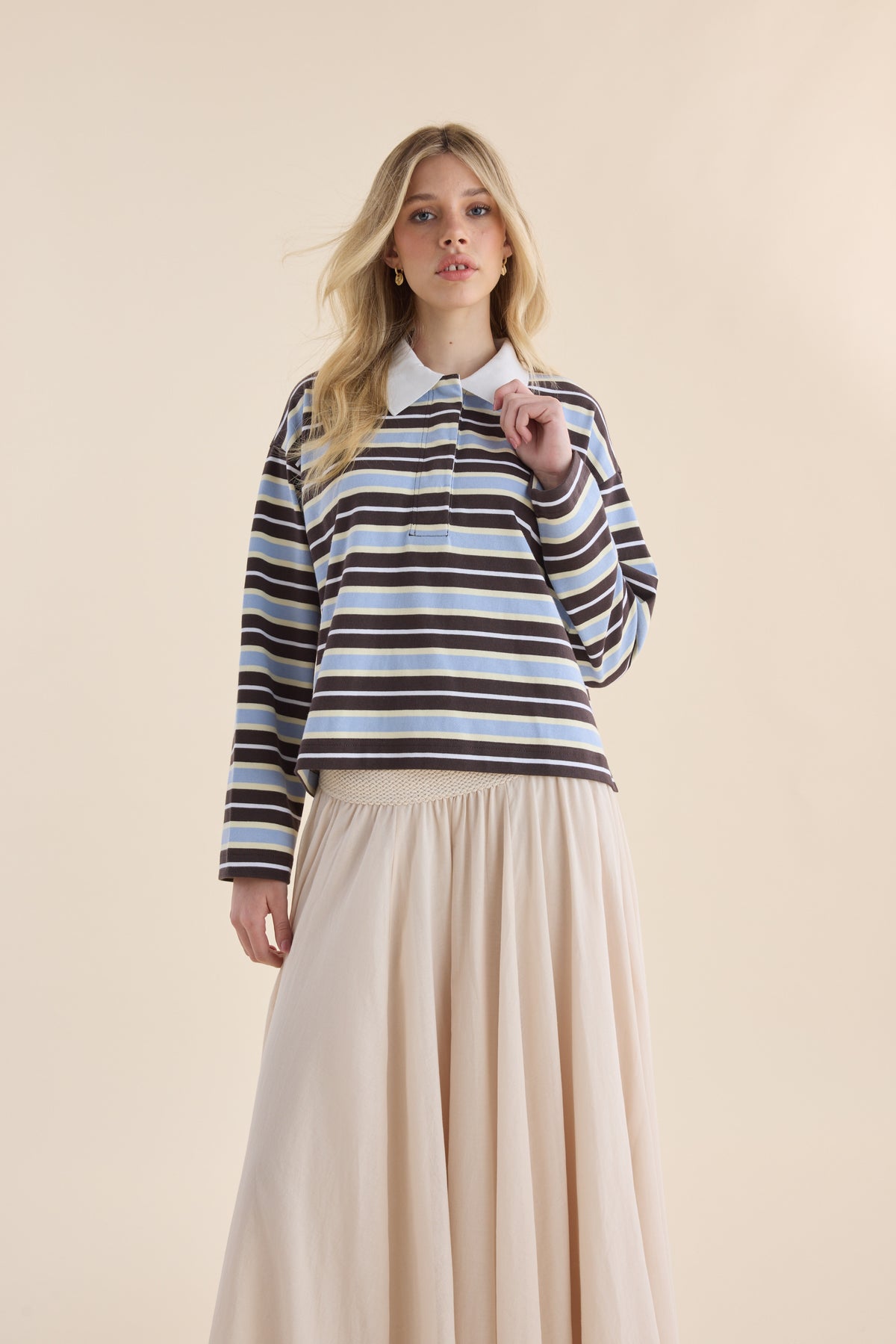 Woman in Elementary Polo Top, Ice Blue Stripe, and beige skirt shows a relaxed silhouette.