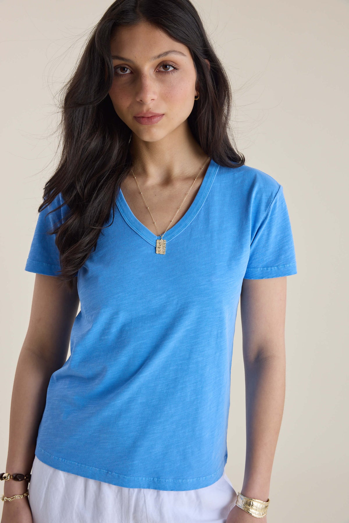 Woman with long dark hair in an Elementary Organic Cotton Slub V Neck Tee and pendant necklace.