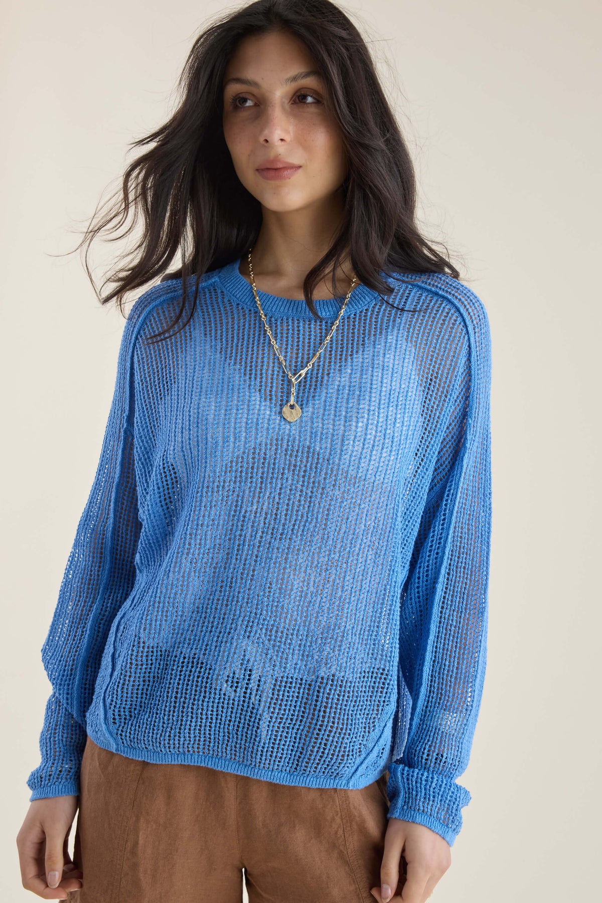 Woman wears blue Elementary Linen Knit Detail Sweater with brown pants and necklaces.