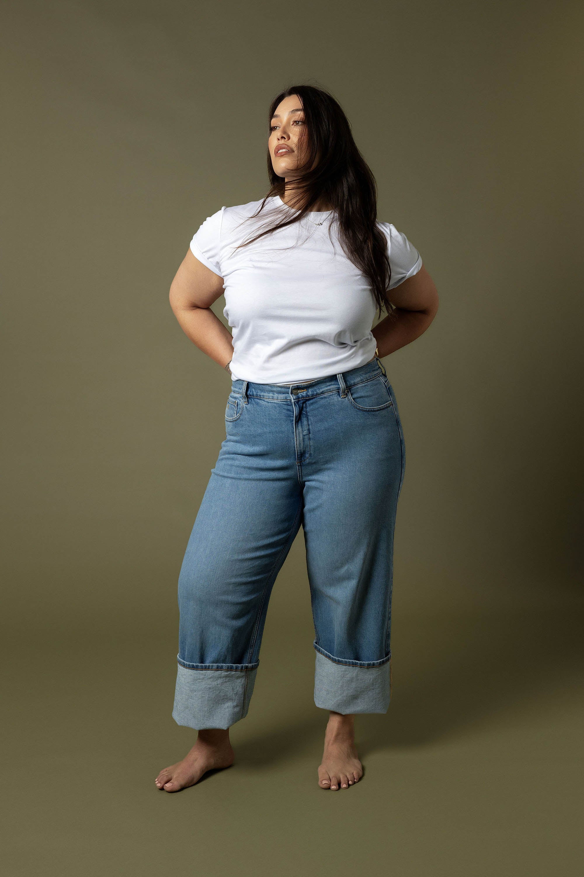 Woman in Nevada Wide Jeans by Max and white tee stands barefoot against a plain background.