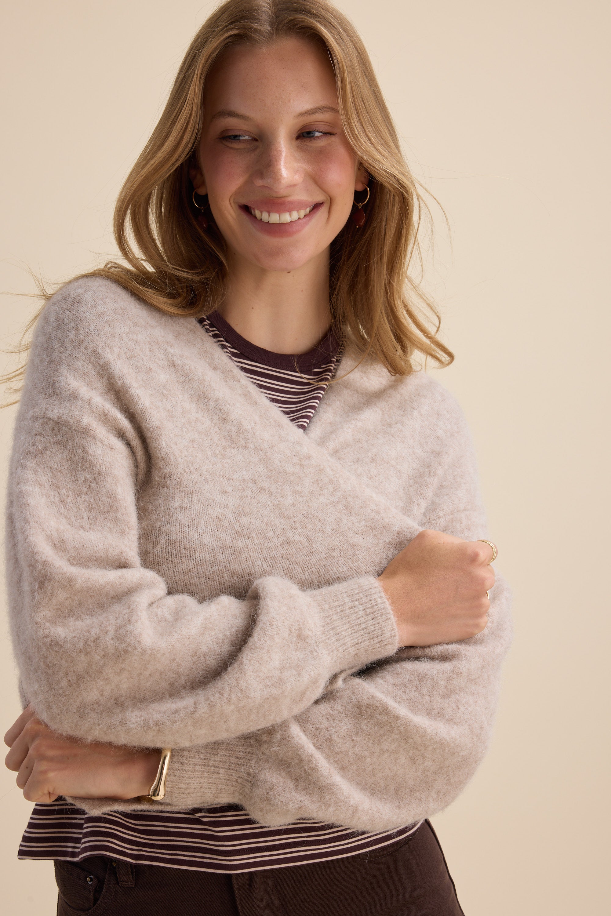 Woman smiles in Max’s The Ultimate Luxe Cardigan, layered over a striped top, arms crossed.