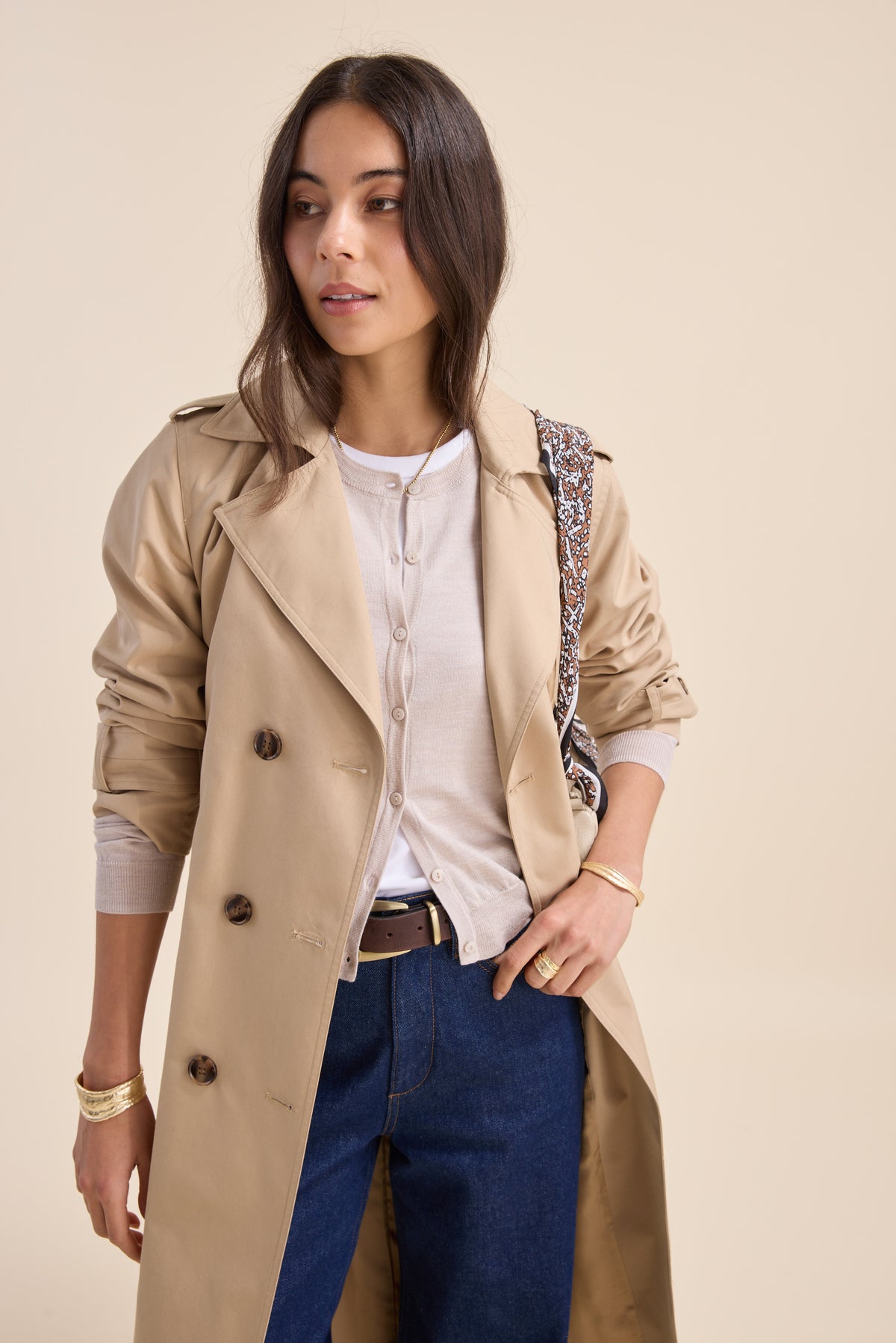 Woman in beige trench, white top, jeans, with a Max Merino Silk Cardigan draped over her shoulder.