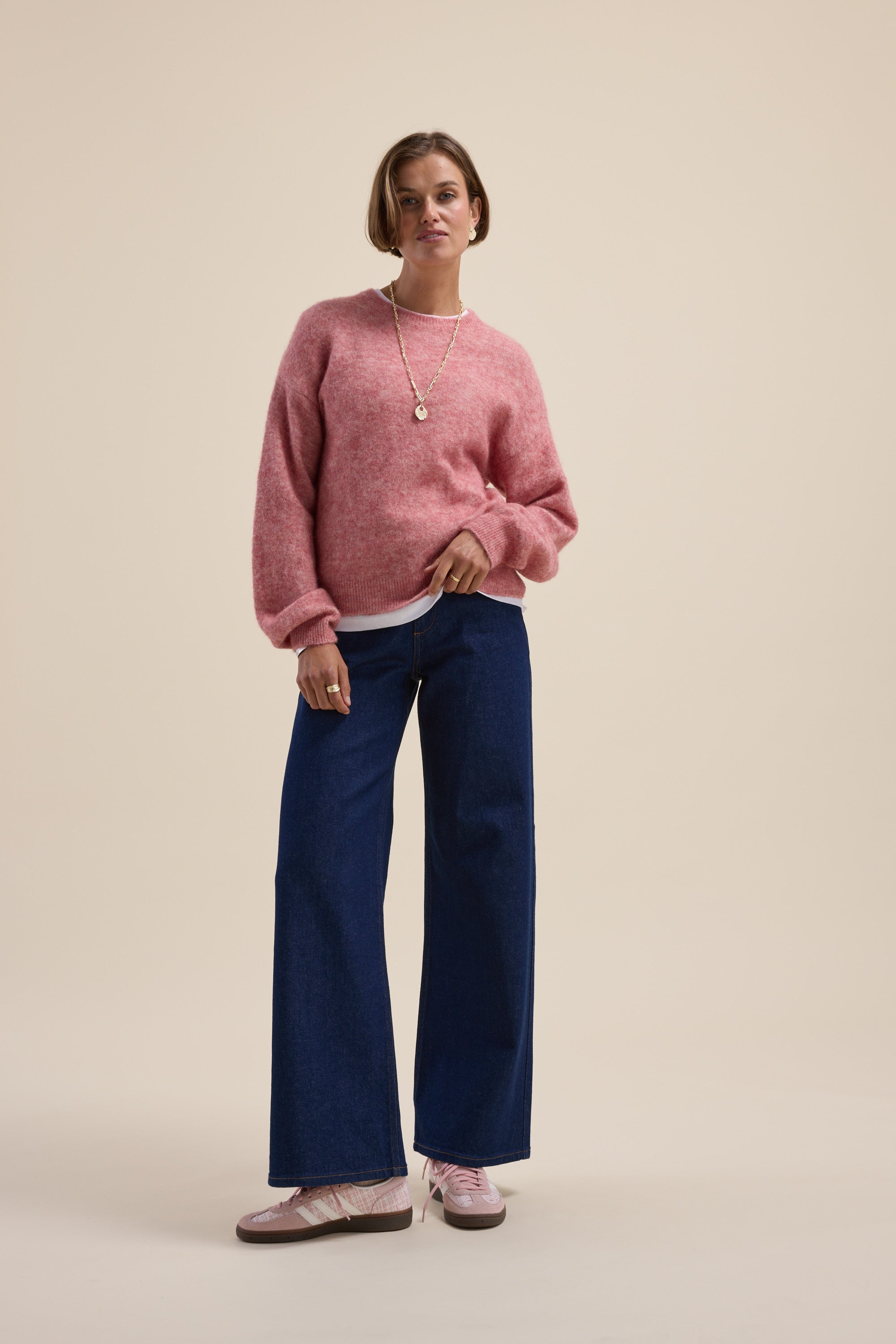 Woman in a Max Hayley Luxe Whisper Crew Neck Sweater, wide-leg jeans, and pink sneakers.