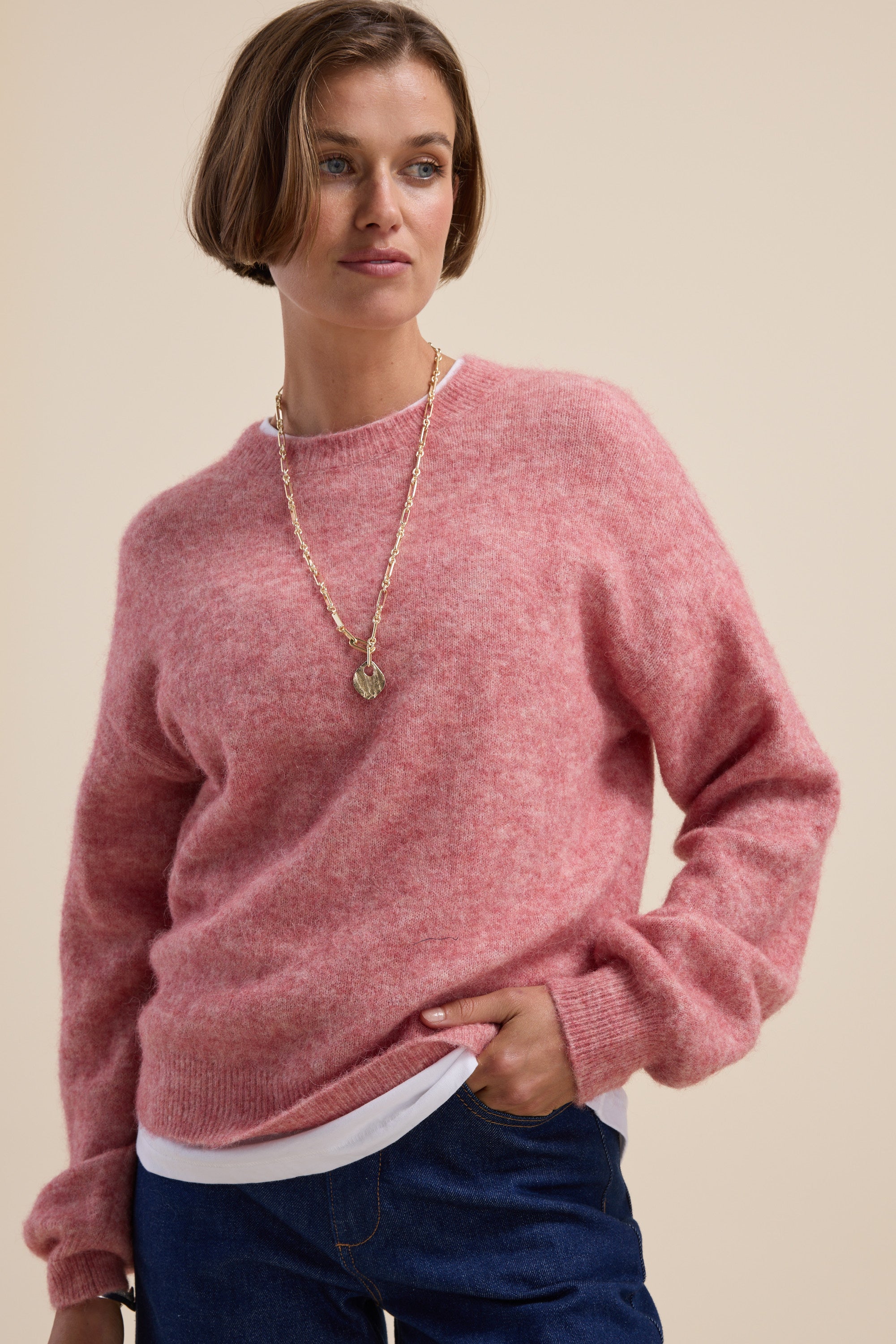Woman wearing Max Hayley Luxe Whisper Crew Neck Sweater in pink, hand in pocket, beige background.