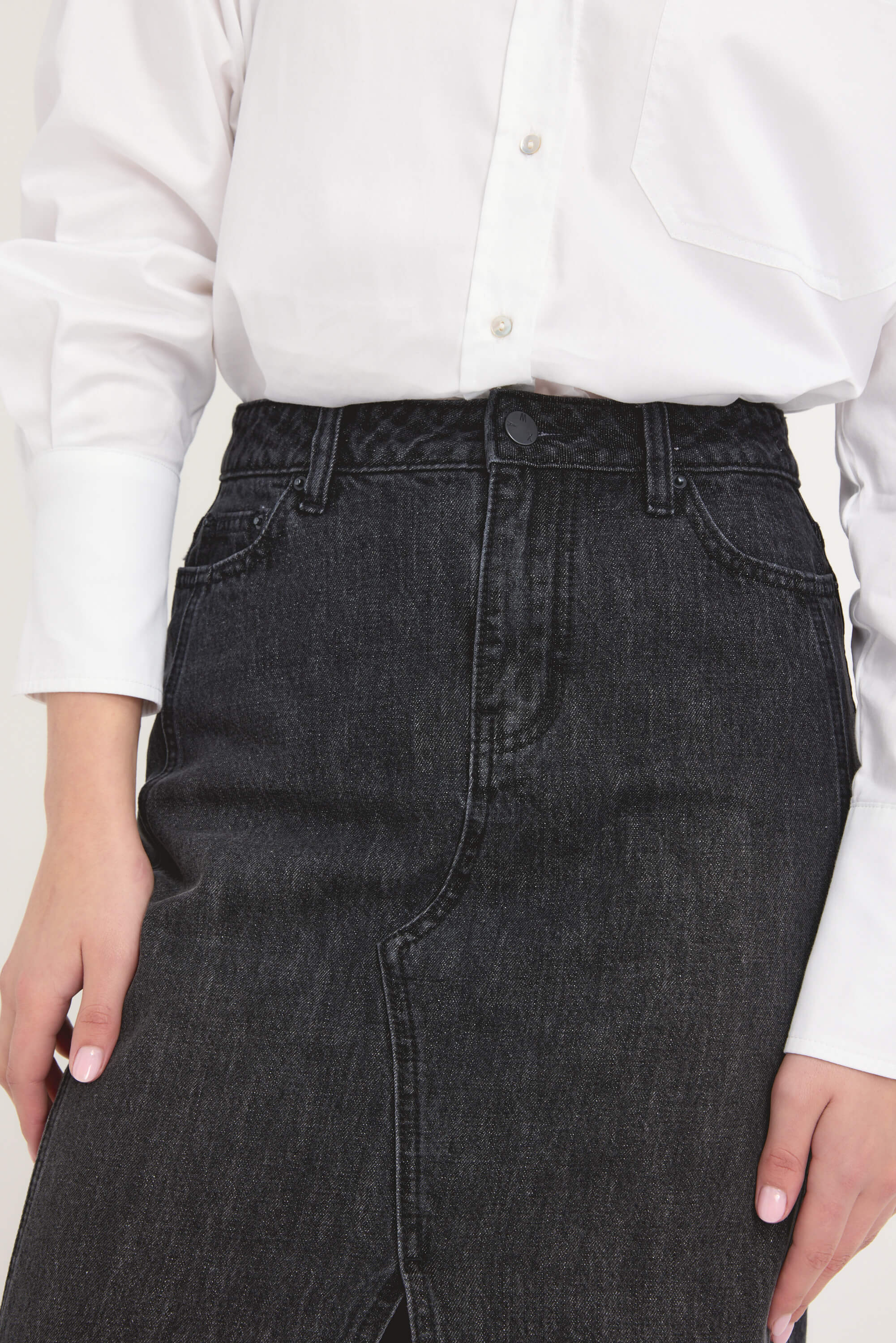 A person wears the Paris Maxi Denim Skirt by Max, styled with a white button-up shirt. The photo, cropped from shoulders to thighs, showcases the classic and sustainable dark eco denim design.