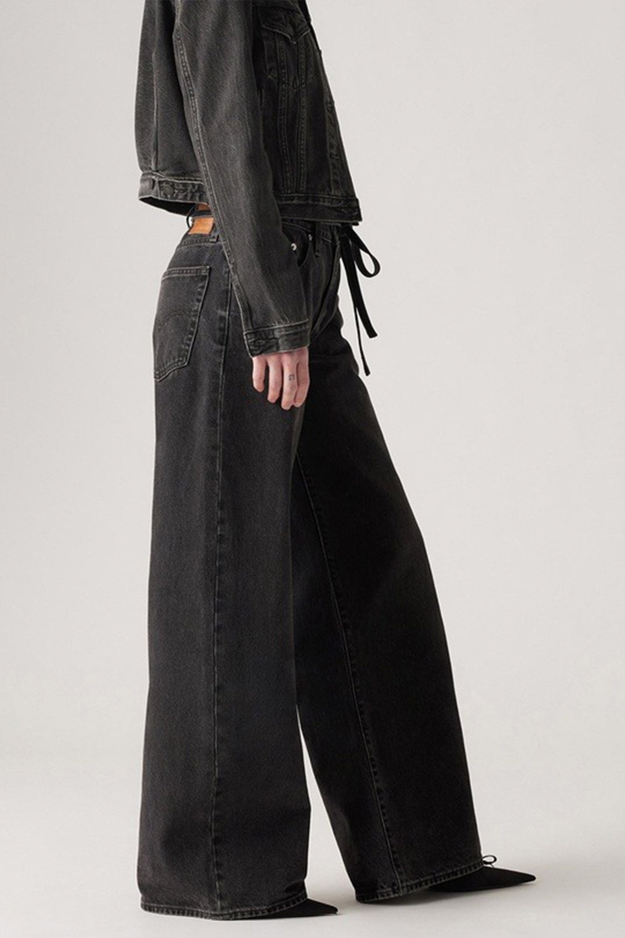 A person wears Levi's XL Straight Jeans, featuring a high-waisted, oversized fit with an adjustable tie waistband. Only the lower half of the body and part of the torso are visible against a plain light background.