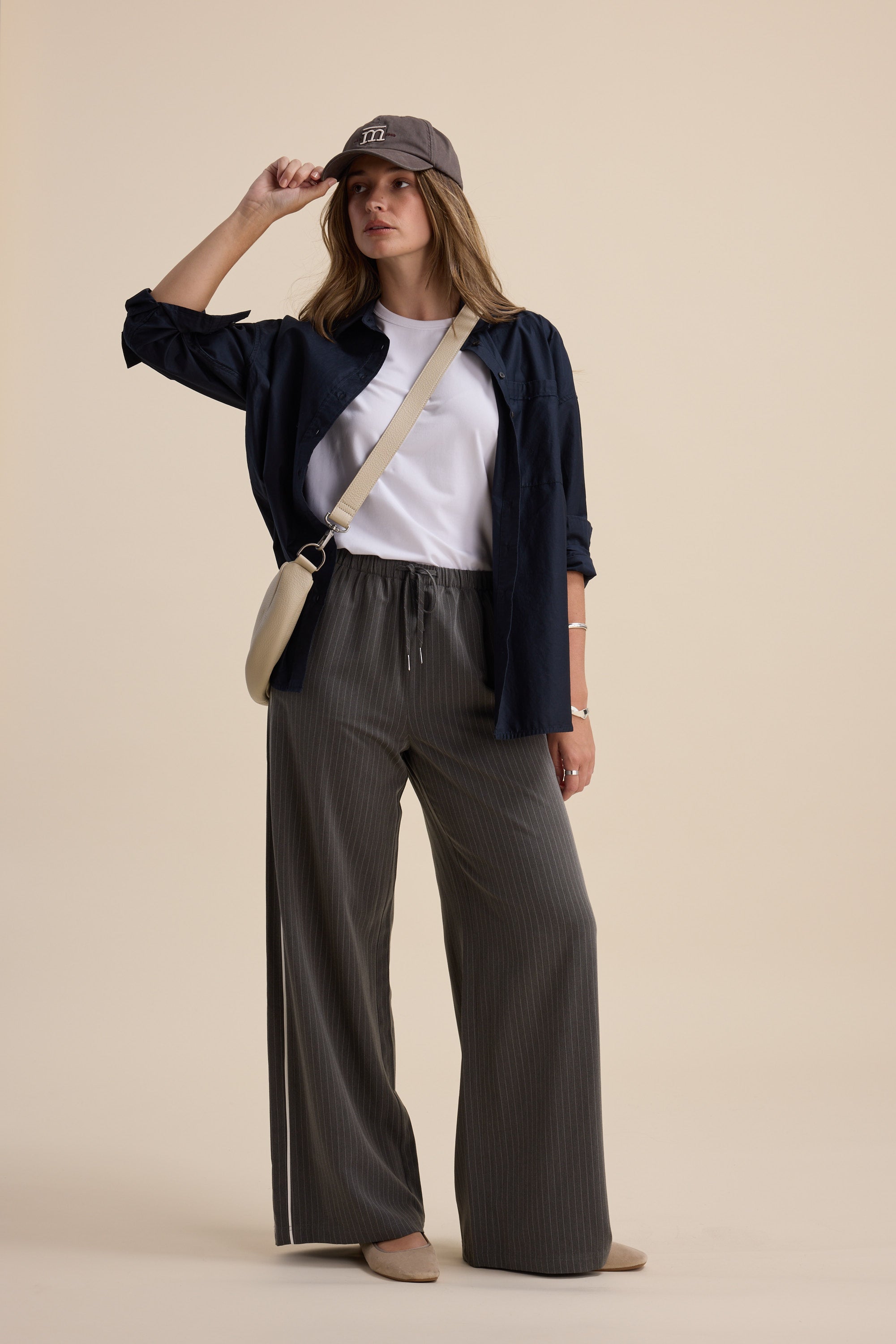 Woman in casual outfit wearing Max The Elevated Jogger, navy shirt, tee, cap, and crossbody bag.