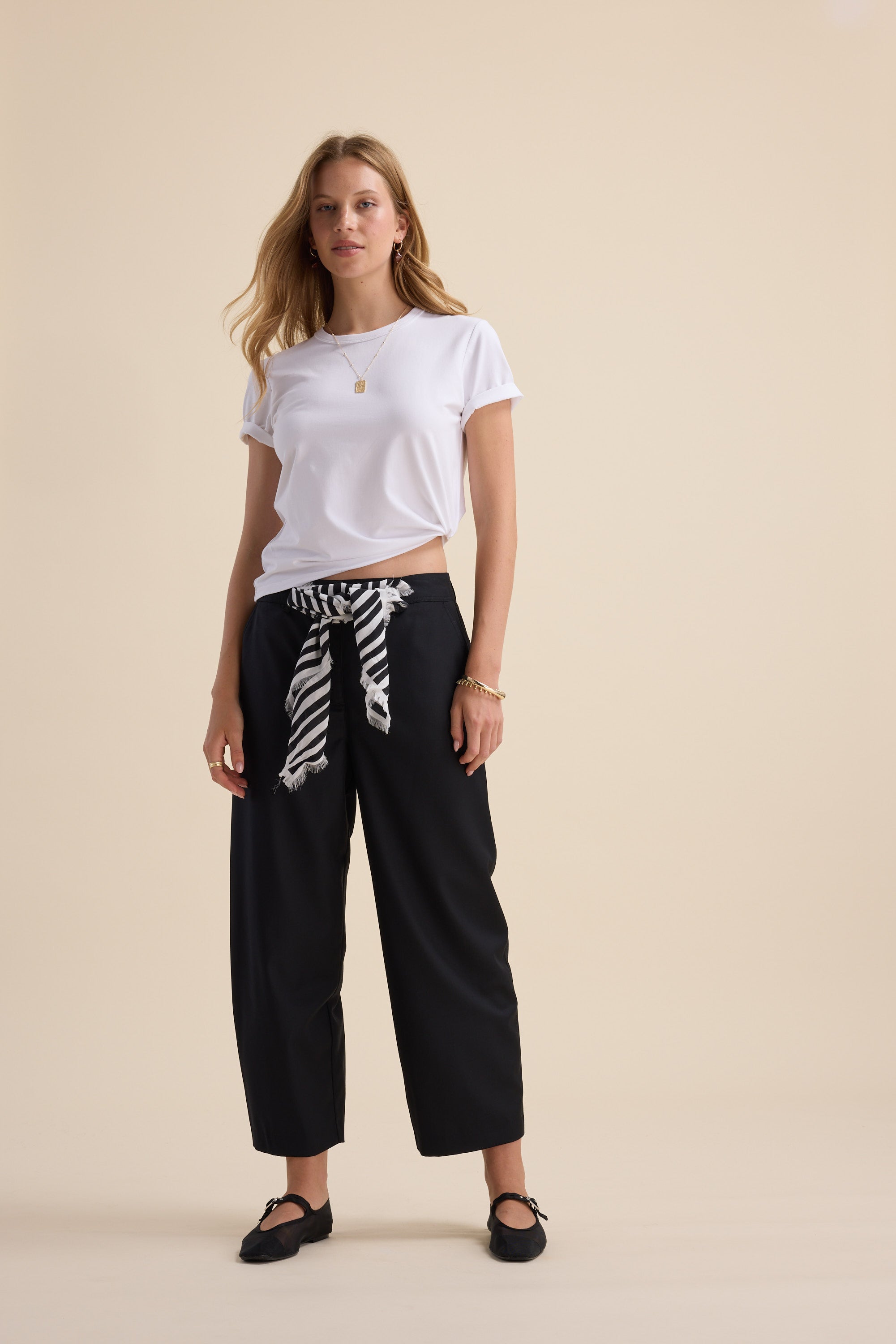 Woman in white tee, Max The Wool Blend Barrel Leg Pants, and black shoes on beige background.