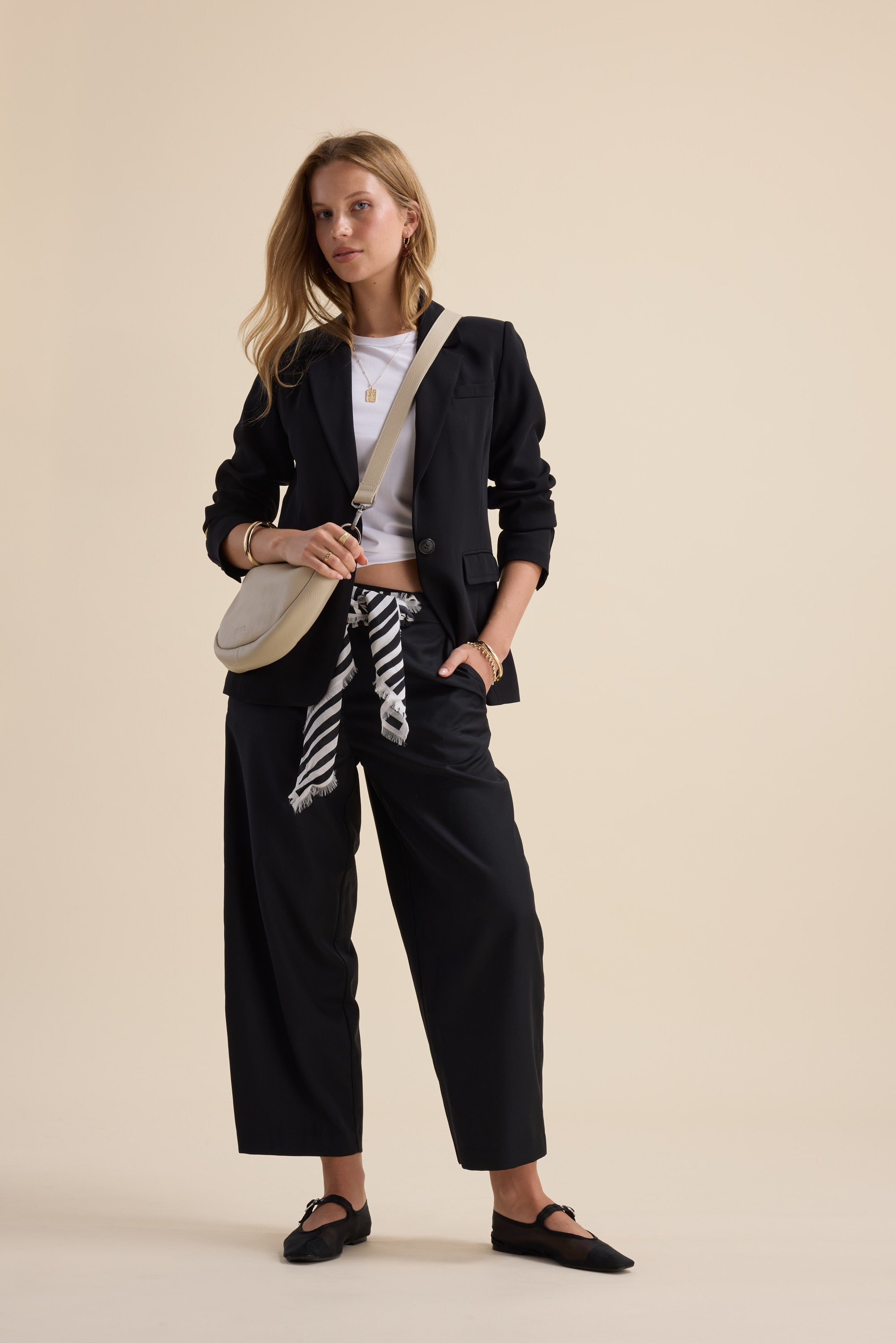 Woman in Max's Wool Blend Barrel Leg Pants, white top, crossbody bag, and flat shoes.