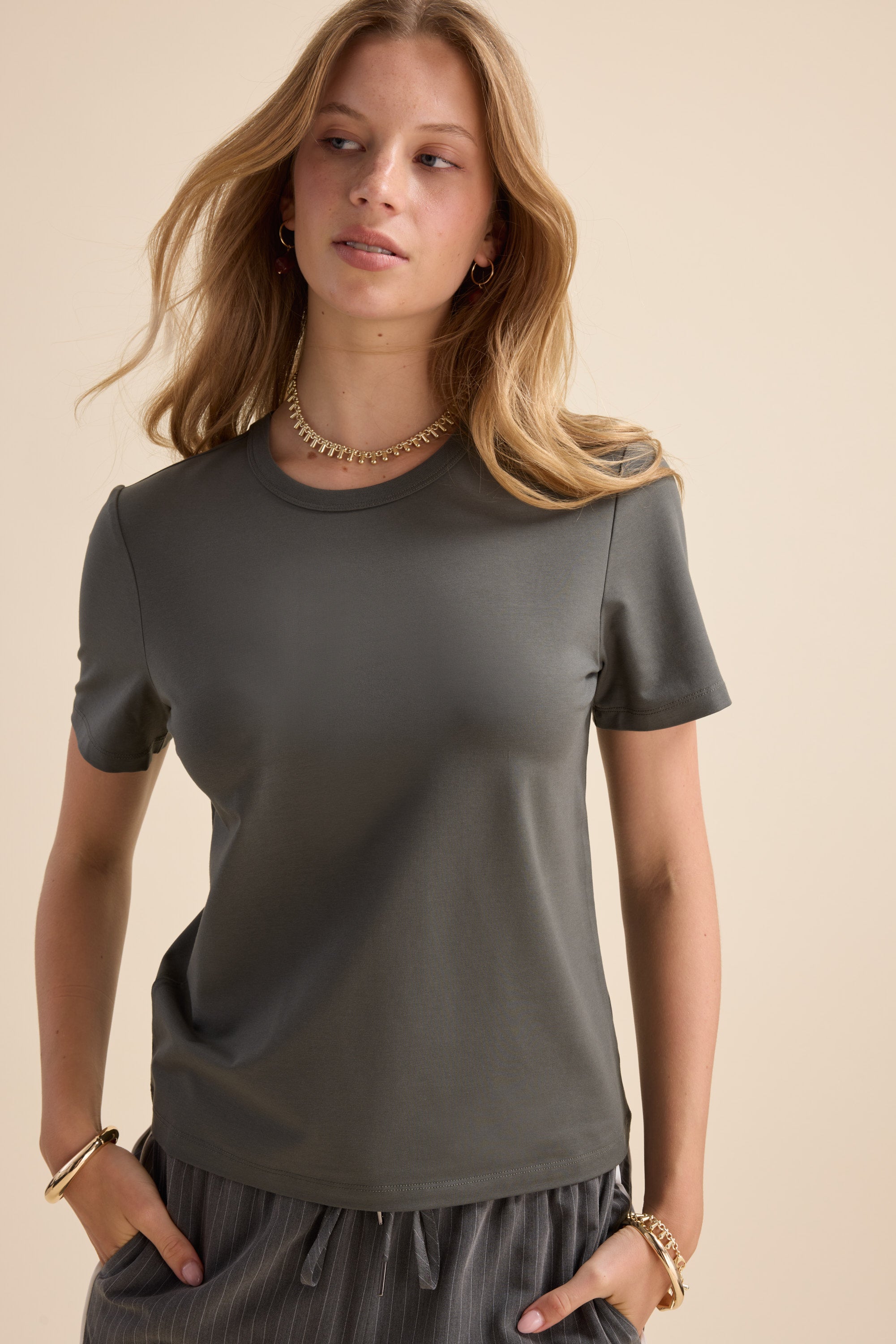 Woman in Max's Perfect Short Sleeve Crew Neck Tee and striped pants, with gold jewelry.