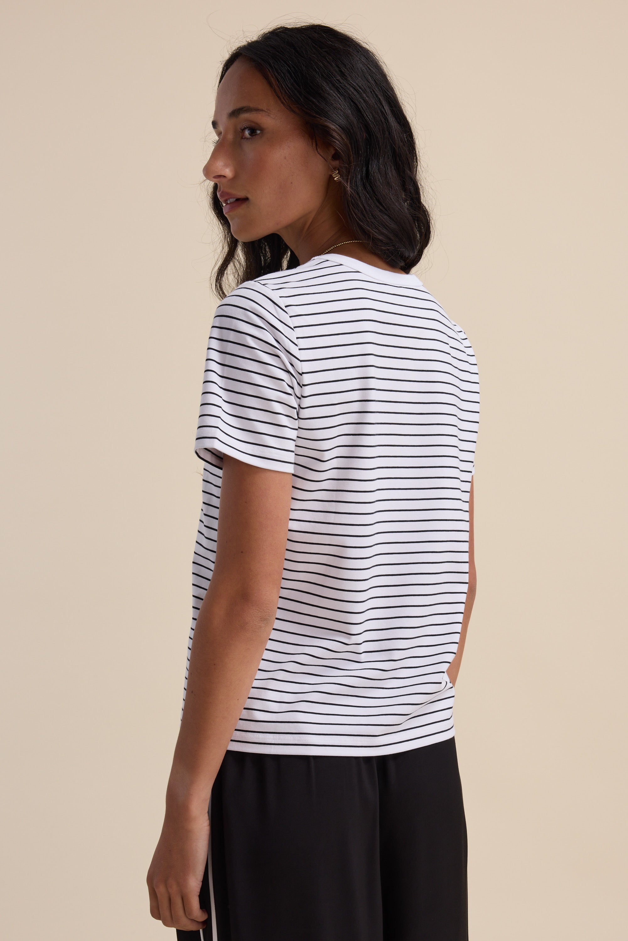 Woman in The Perfect Short Sleeve Crew Neck Tee by Max, side view, striped, neutral background.
