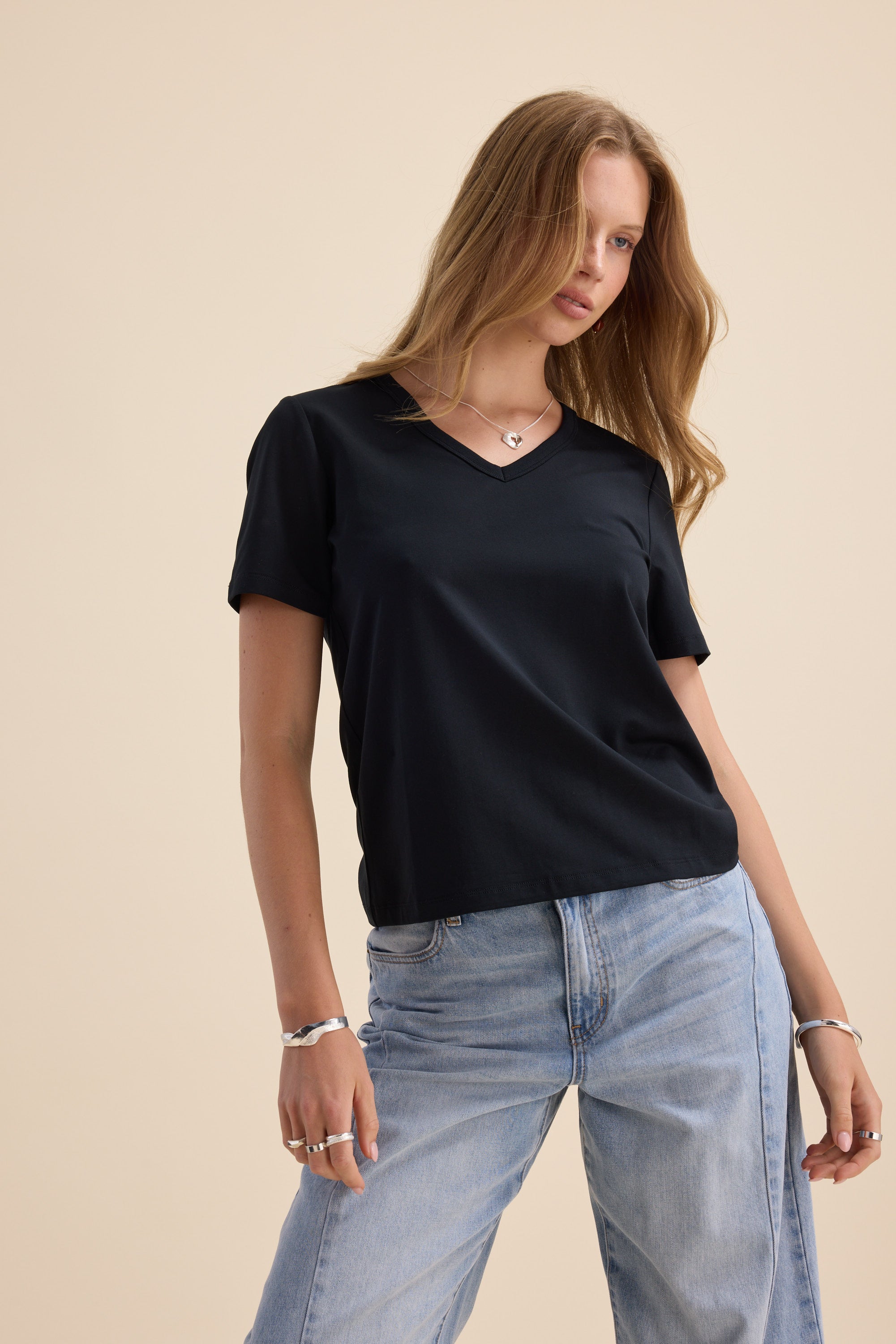 Woman in Max's Perfect Short Sleeve V Neck Tee and light blue jeans showcases a wardrobe staple.
