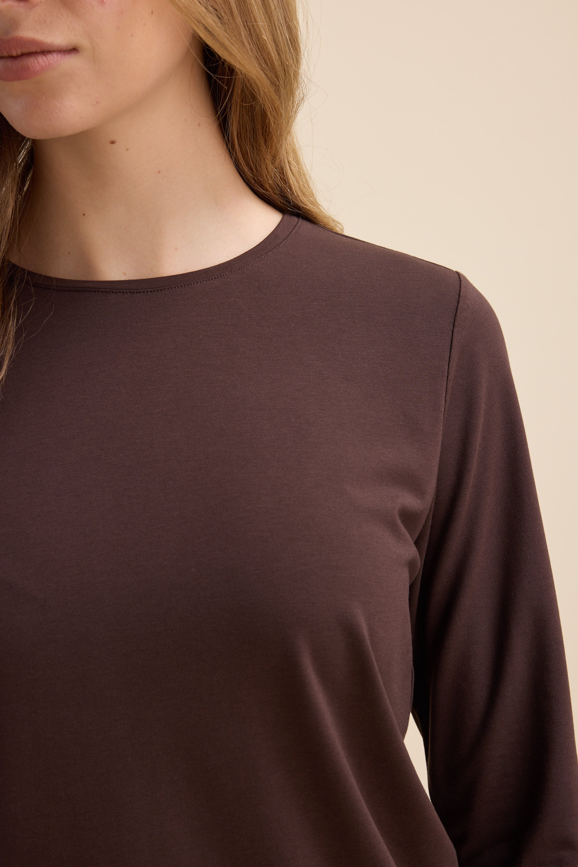 Woman wears The Perfect Long Sleeve Crew Tee by Max in brown, shown from shoulders up.