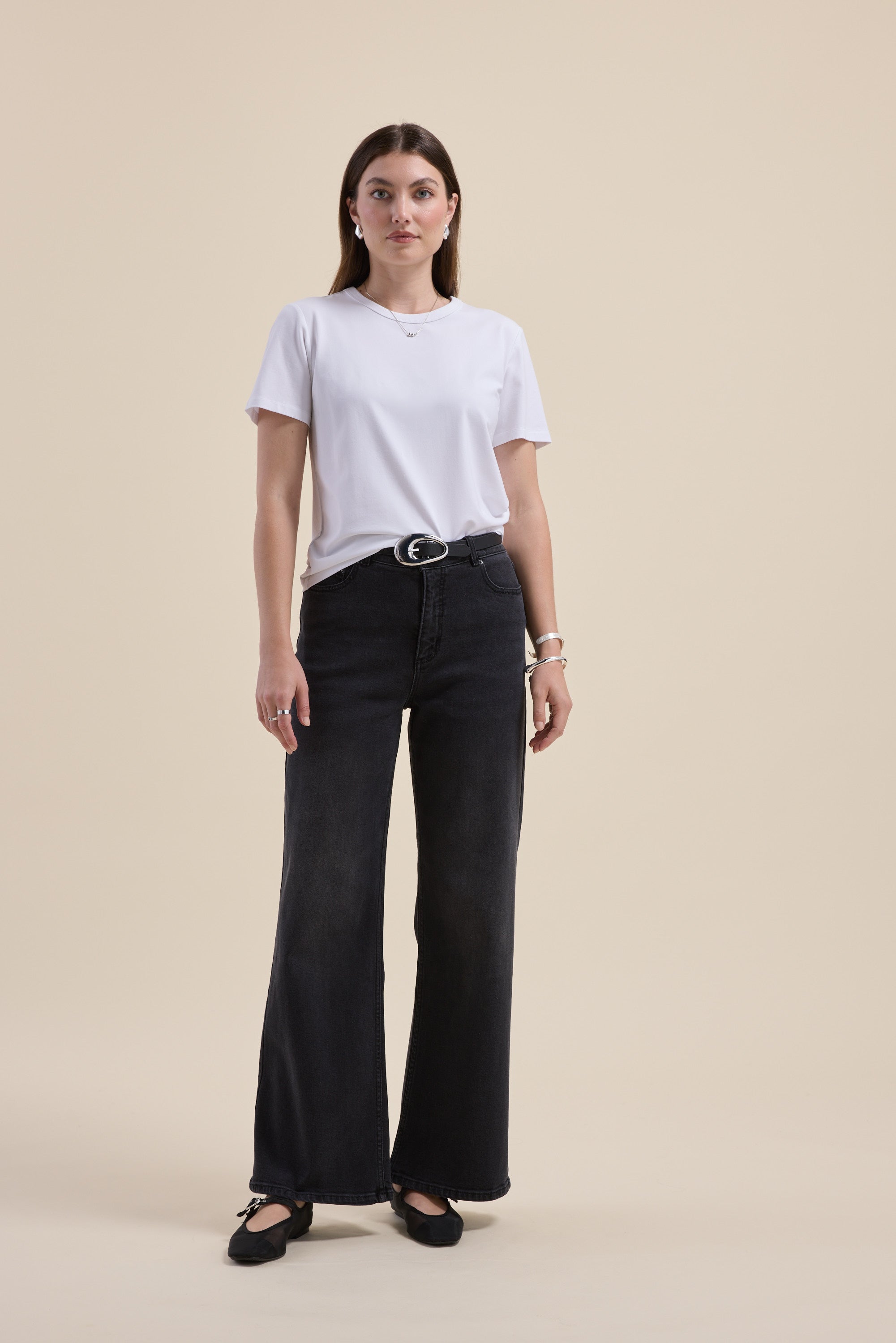 Woman wearing Max’s The Mid Rise Wide Leg Jeans in sustainable denim, white tee, beige backdrop.