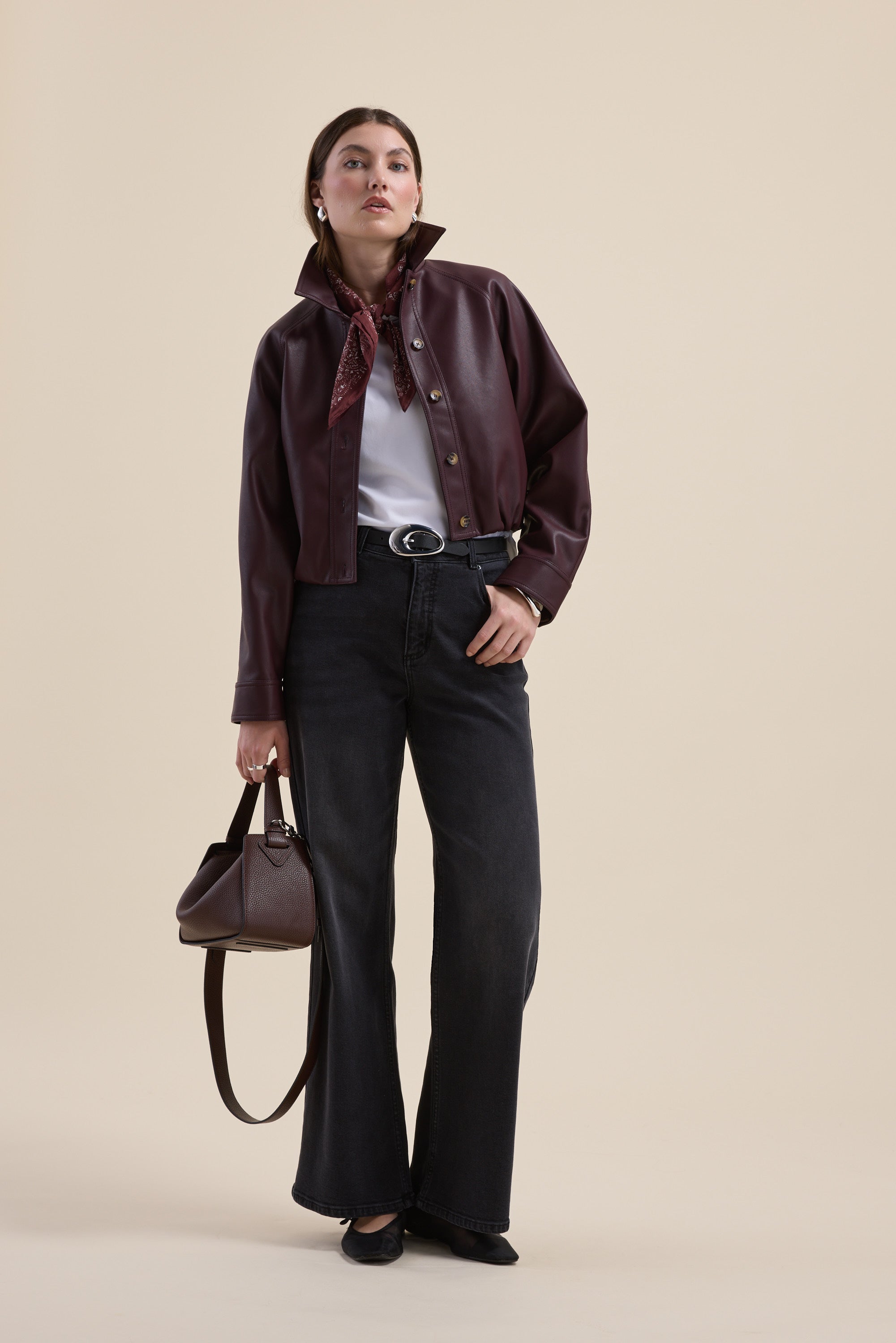Woman in maroon jacket, scarf, holding bag, wearing Max's The Mid Rise Wide Leg Jeans and black shoes.