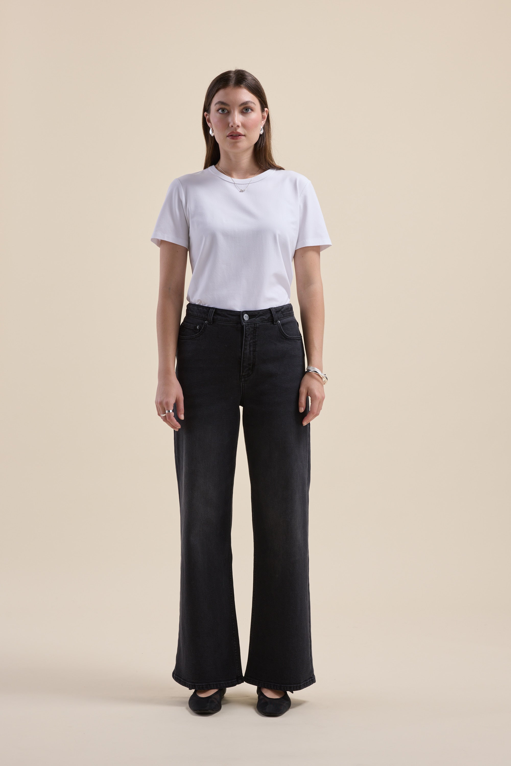 Woman in The Mid Rise Wide Leg Jeans by Max and a white tee stands against a beige background.