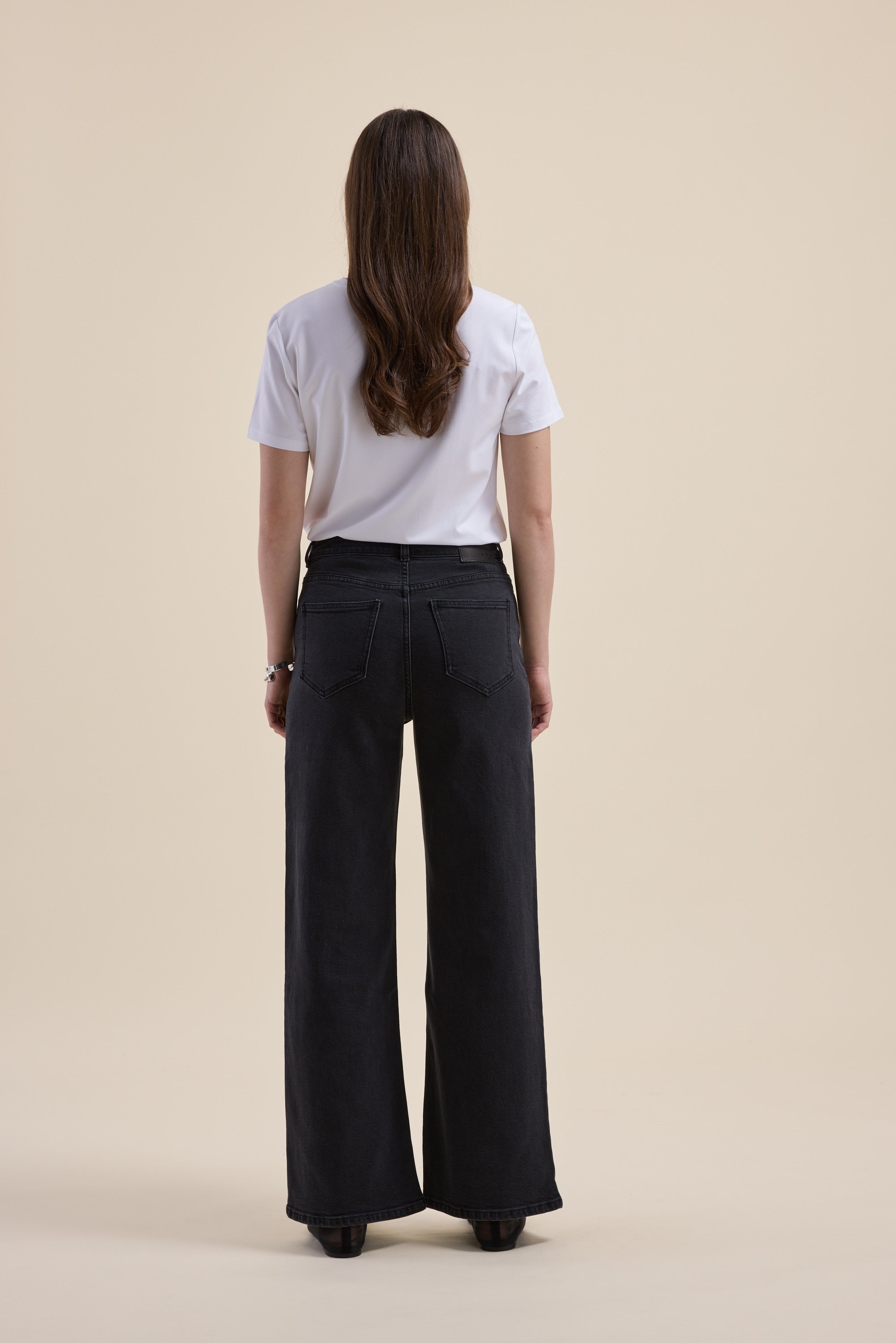 Person with long brown hair in a white shirt and Max The Mid Rise Wide Leg Jeans, facing away.