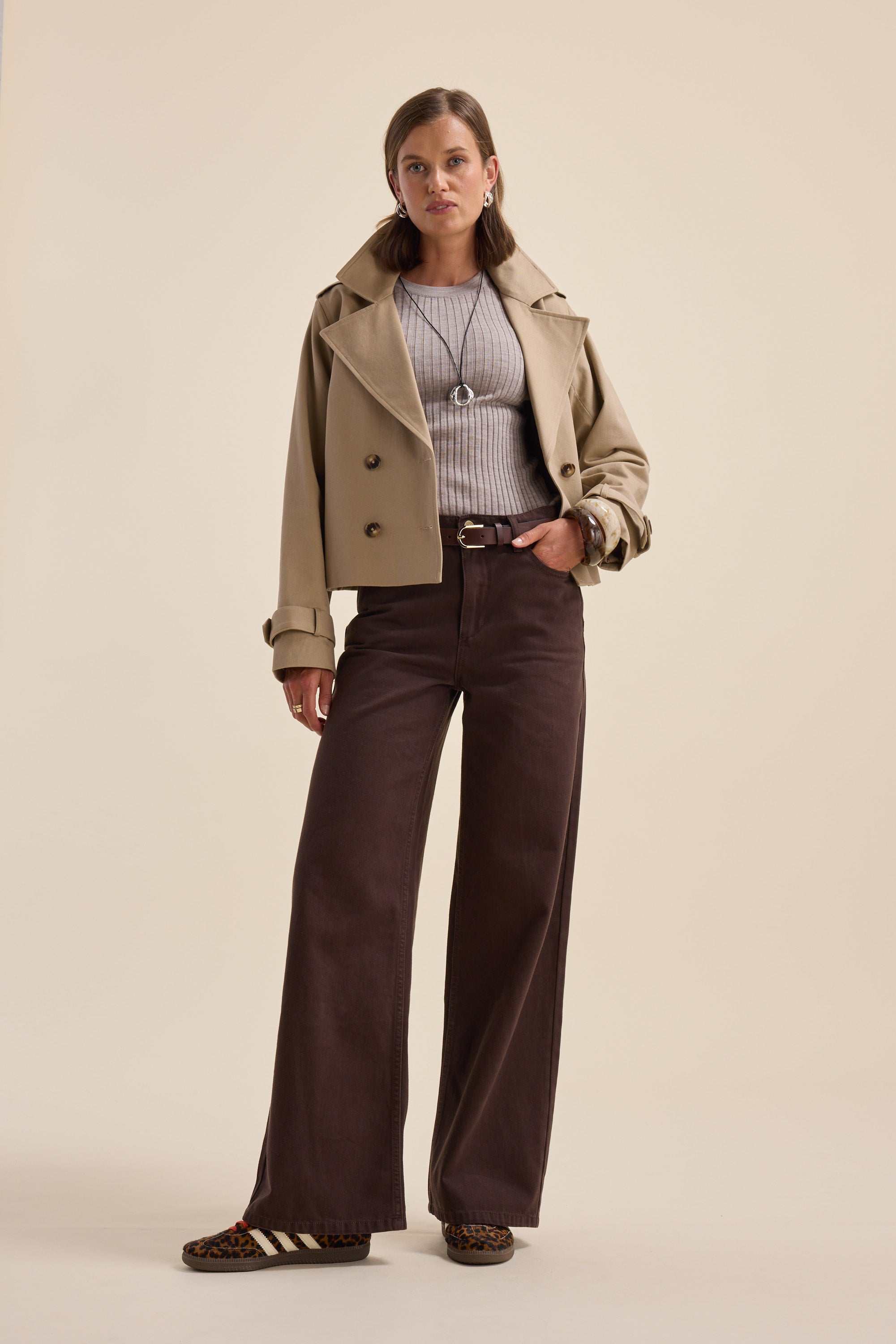 Woman in beige jacket, Elementary ZQ Merino Crew Neck Top, wide brown pants, animal print shoes.