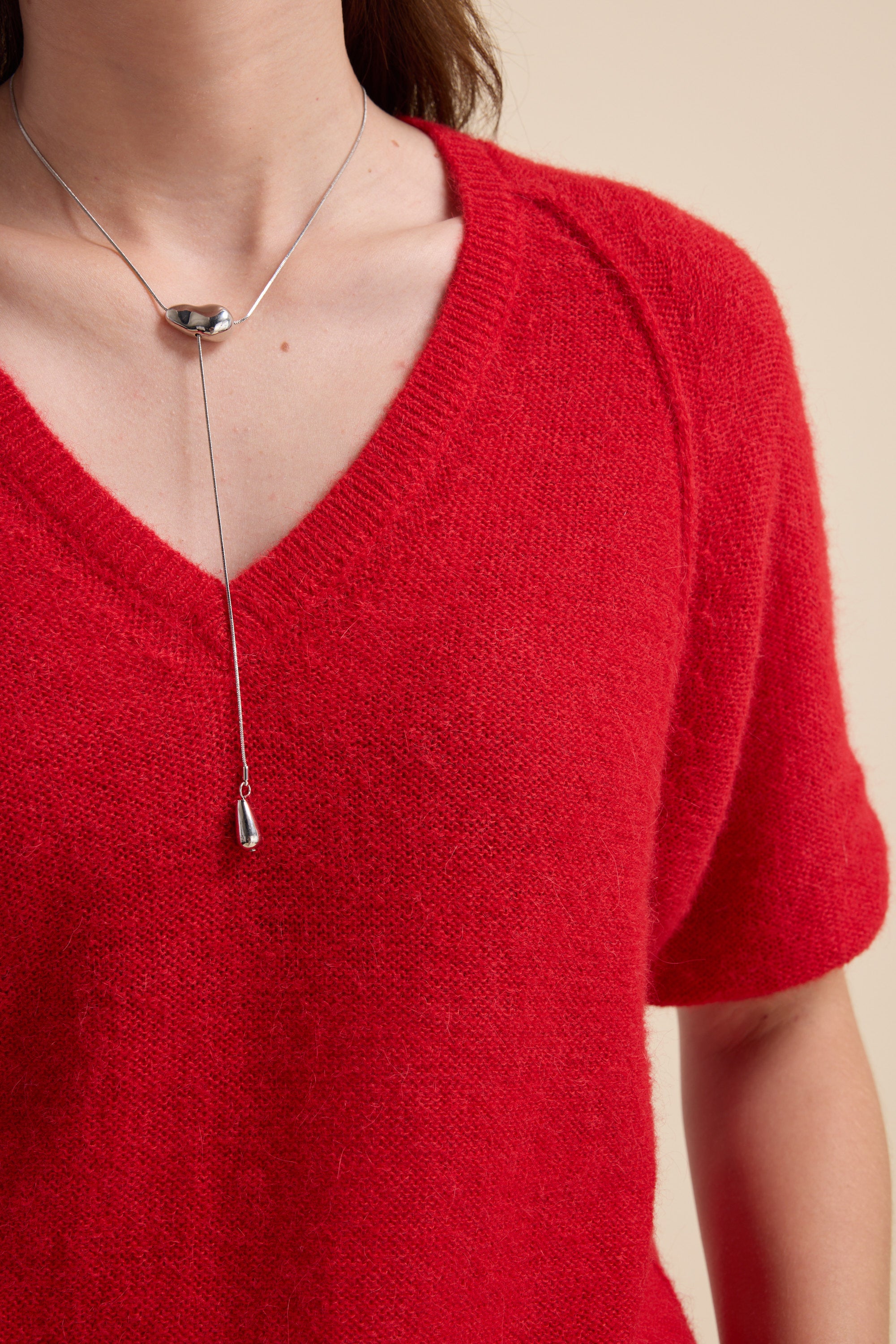 Person in a Max Ivy Knitted V Neck Tee and a silver lariat necklace.
