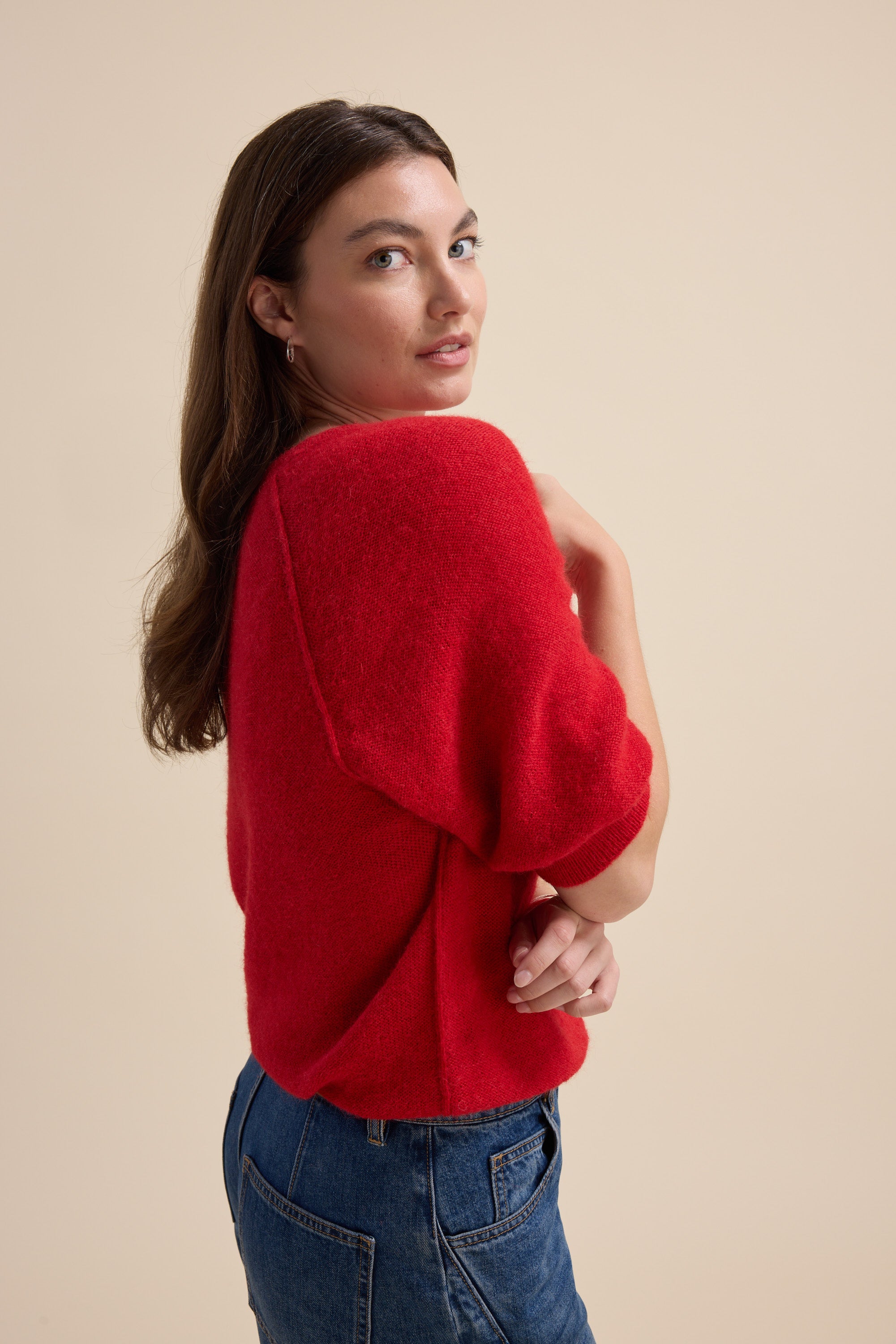 Woman in Max's Ivy Knitted V Neck Tee and jeans poses against a beige background.