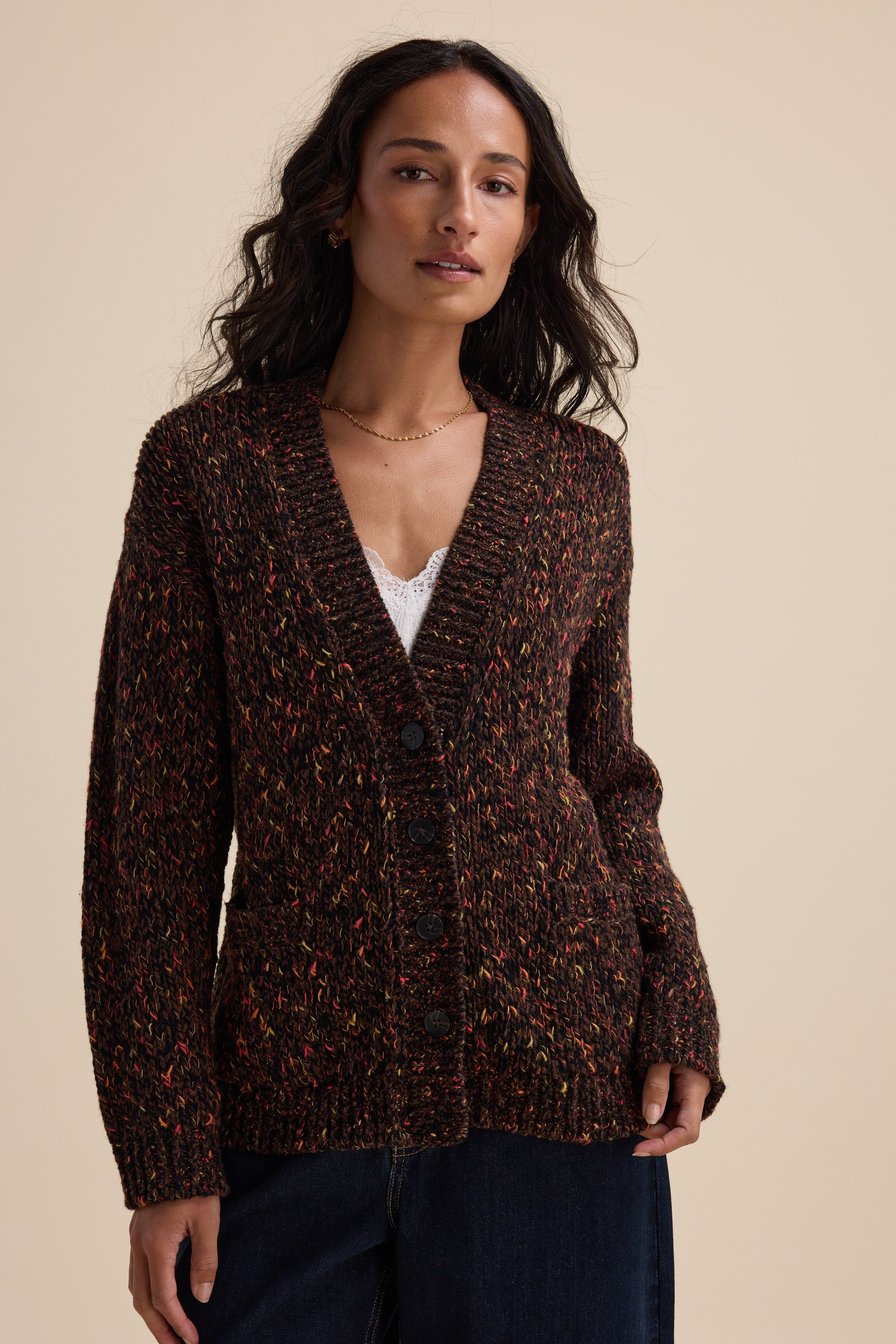Woman in the Elementary Oversized Merino Blend Cardigan over a white top, beige background.