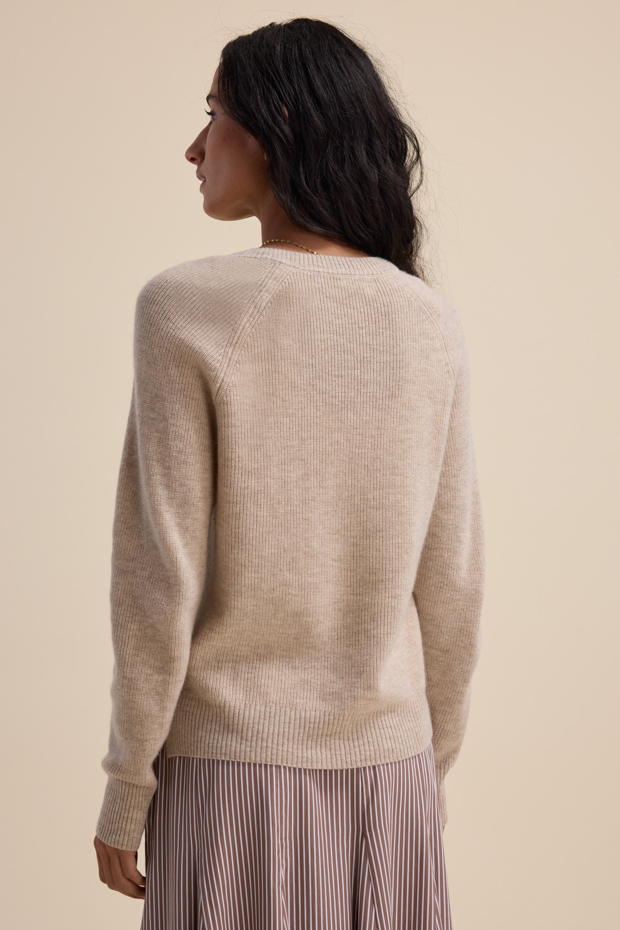 Woman in an Elementary Cashmere Blend V Neck Sweater, seen from the back.