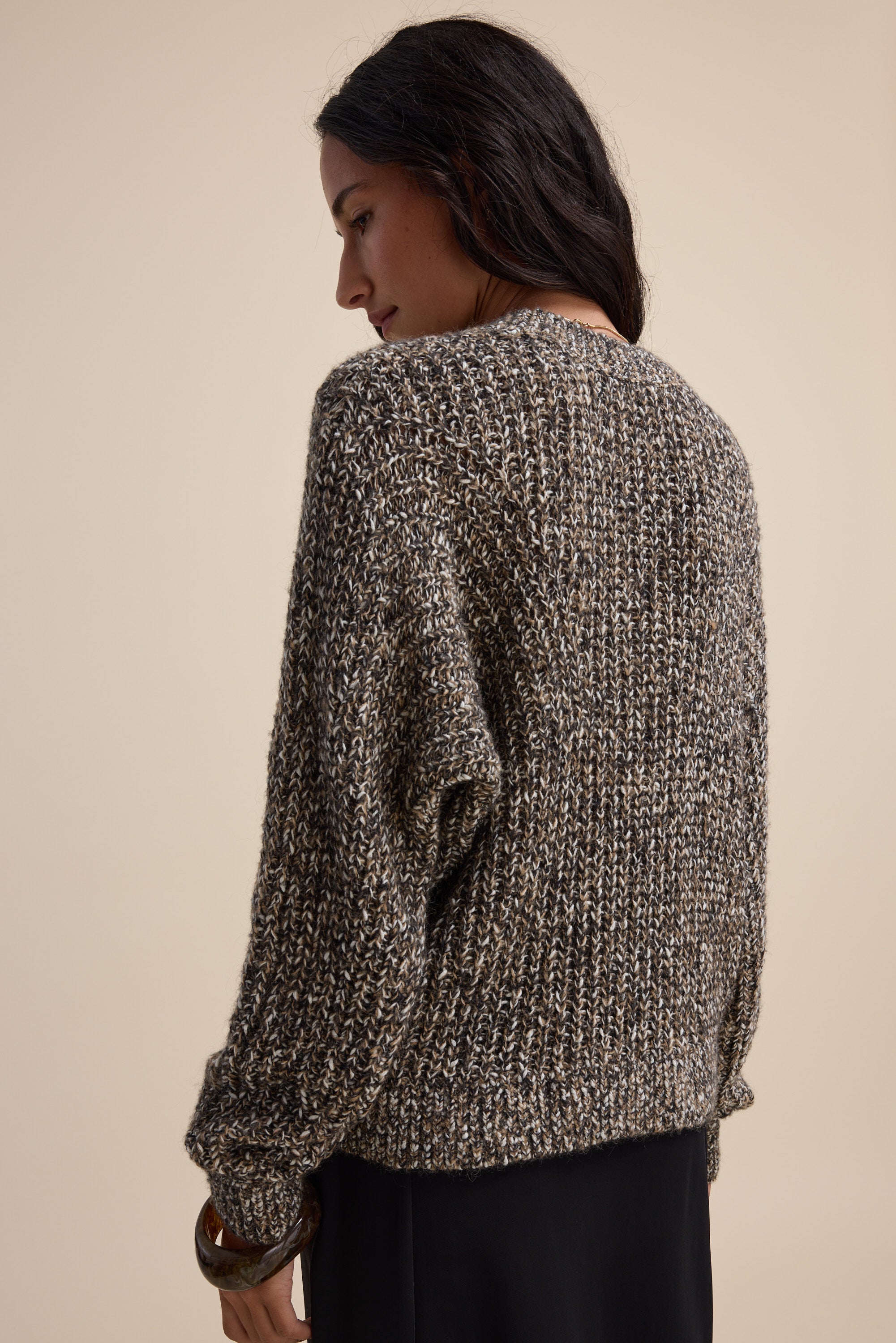 Woman in Elementary Chunky Knit Sweater, relaxed fit, facing away, beige background.