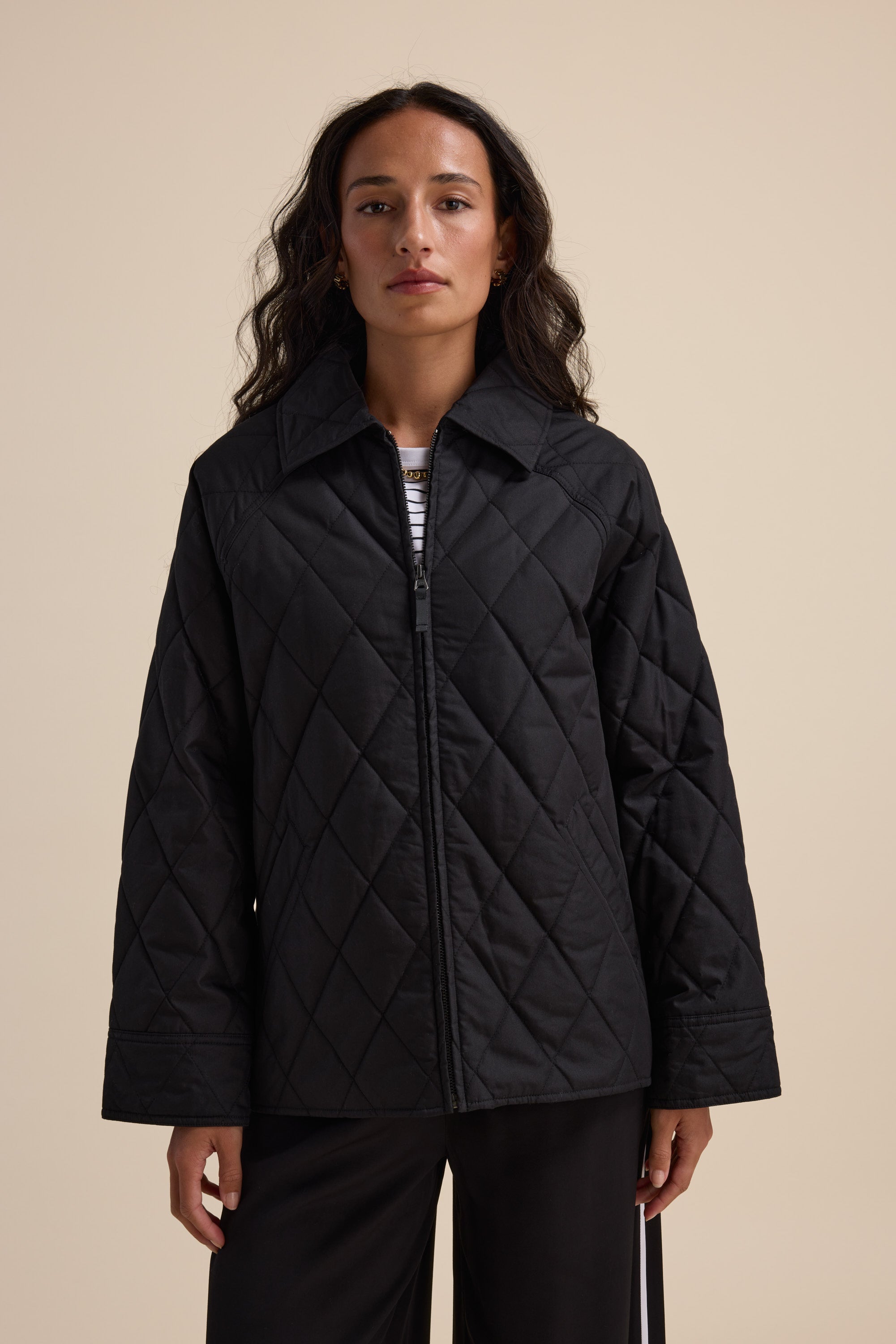 Woman in the Elementary Quilted Puffer by Elementary, posed against a plain beige background.