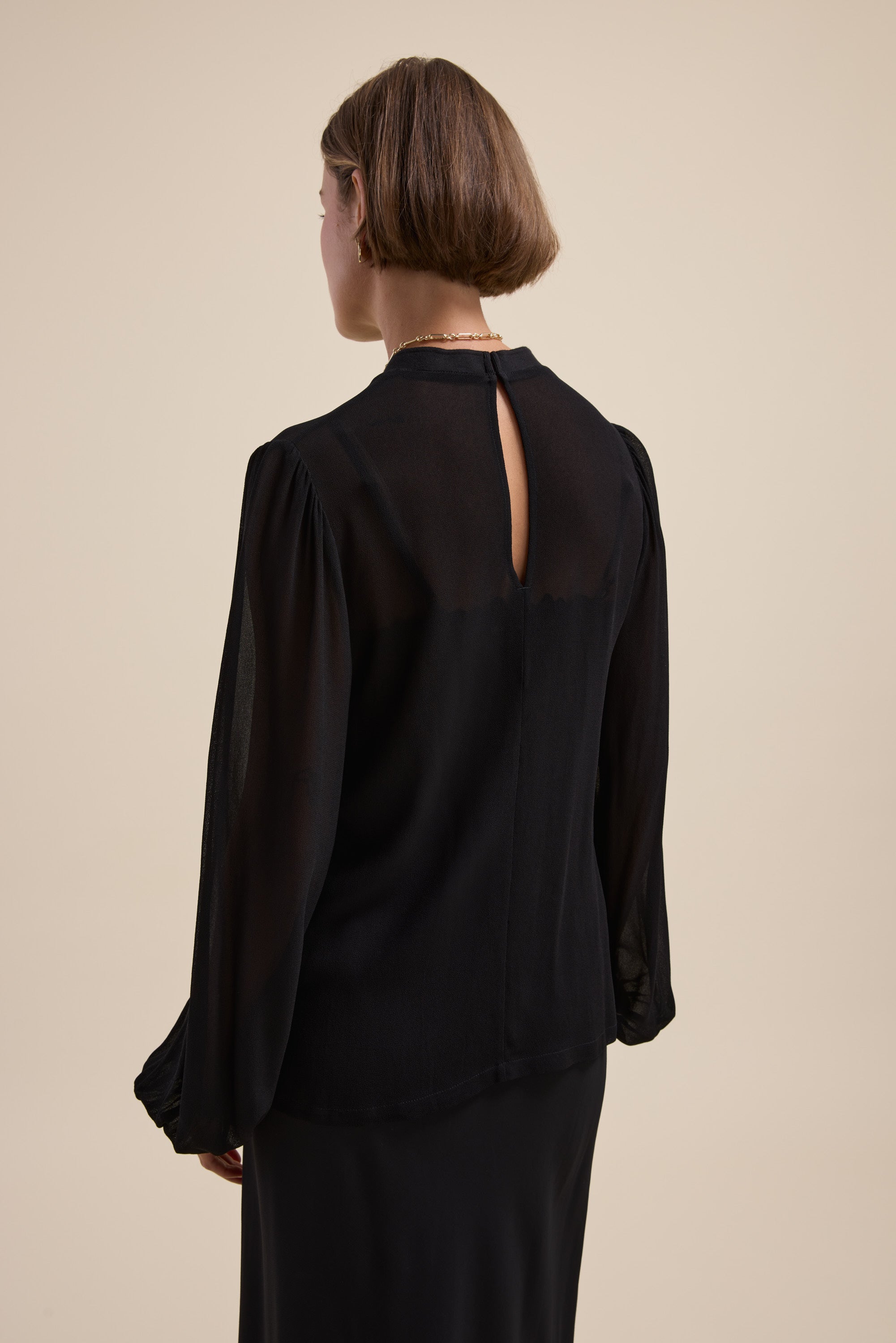 Woman in The Ultimate Layering Top by Max, sheer black, seen from the back.