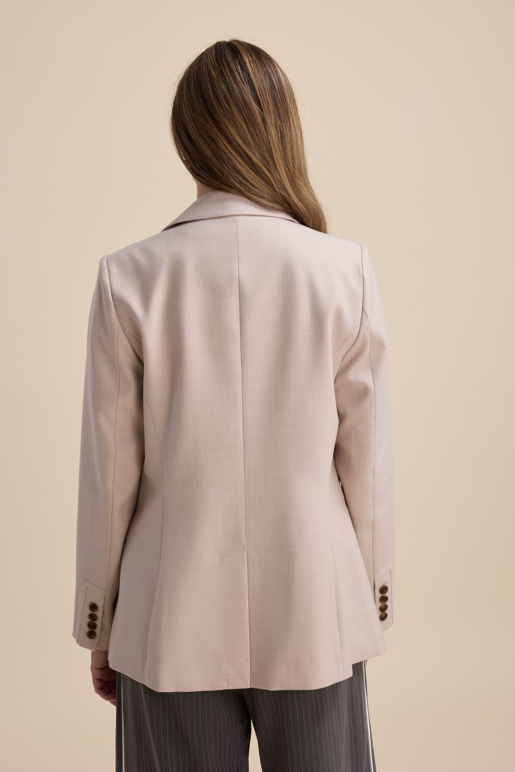 Model wears The Wool Blend Blazer by Max and gray pinstripe pants, back view, plain background.