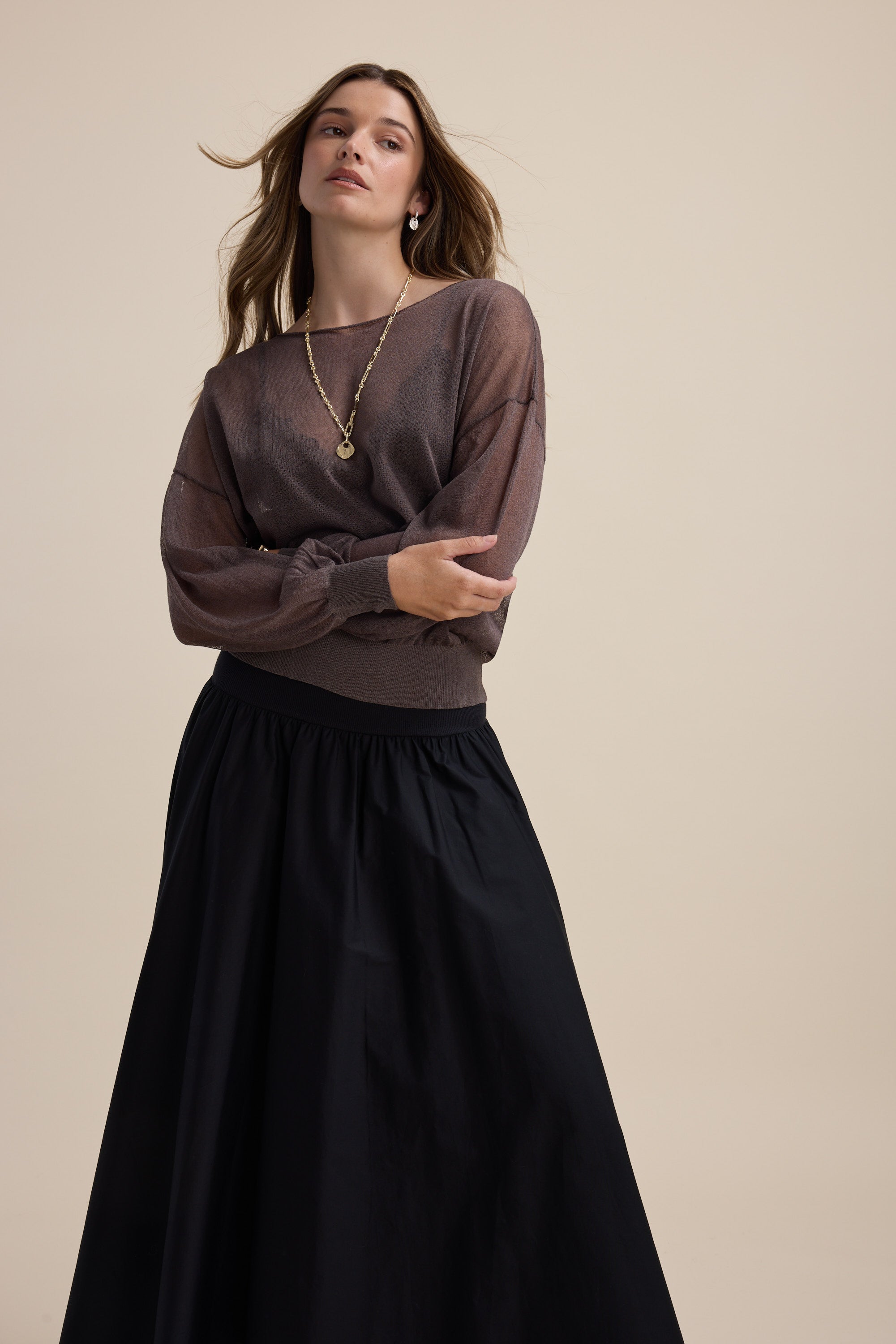 Model wears the Max Addie Sheer Knitted Top with a long black skirt against a beige background.