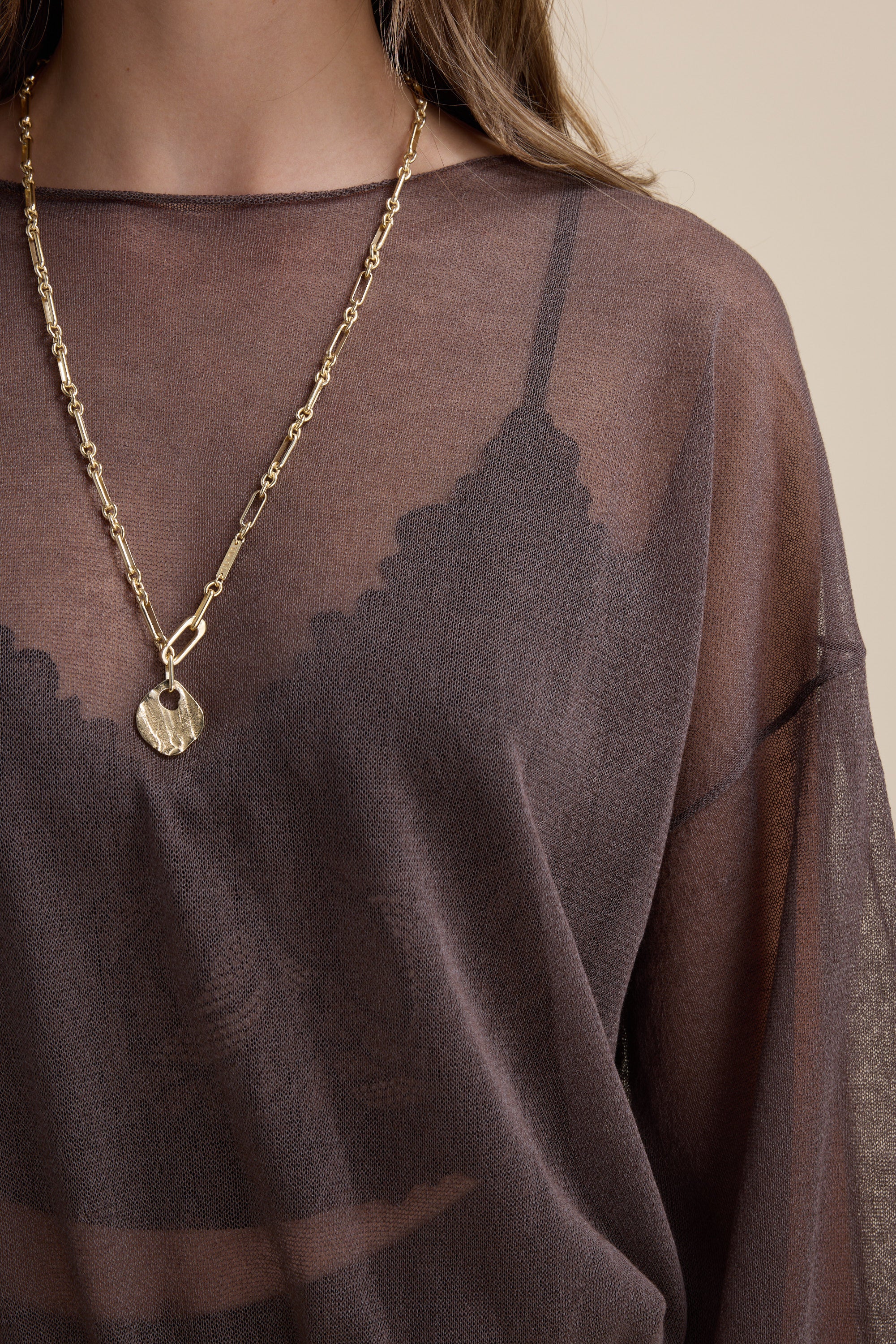 Woman wearing the Addie Sheer Knitted Top by Max, black lace bralette, and gold chain necklace.