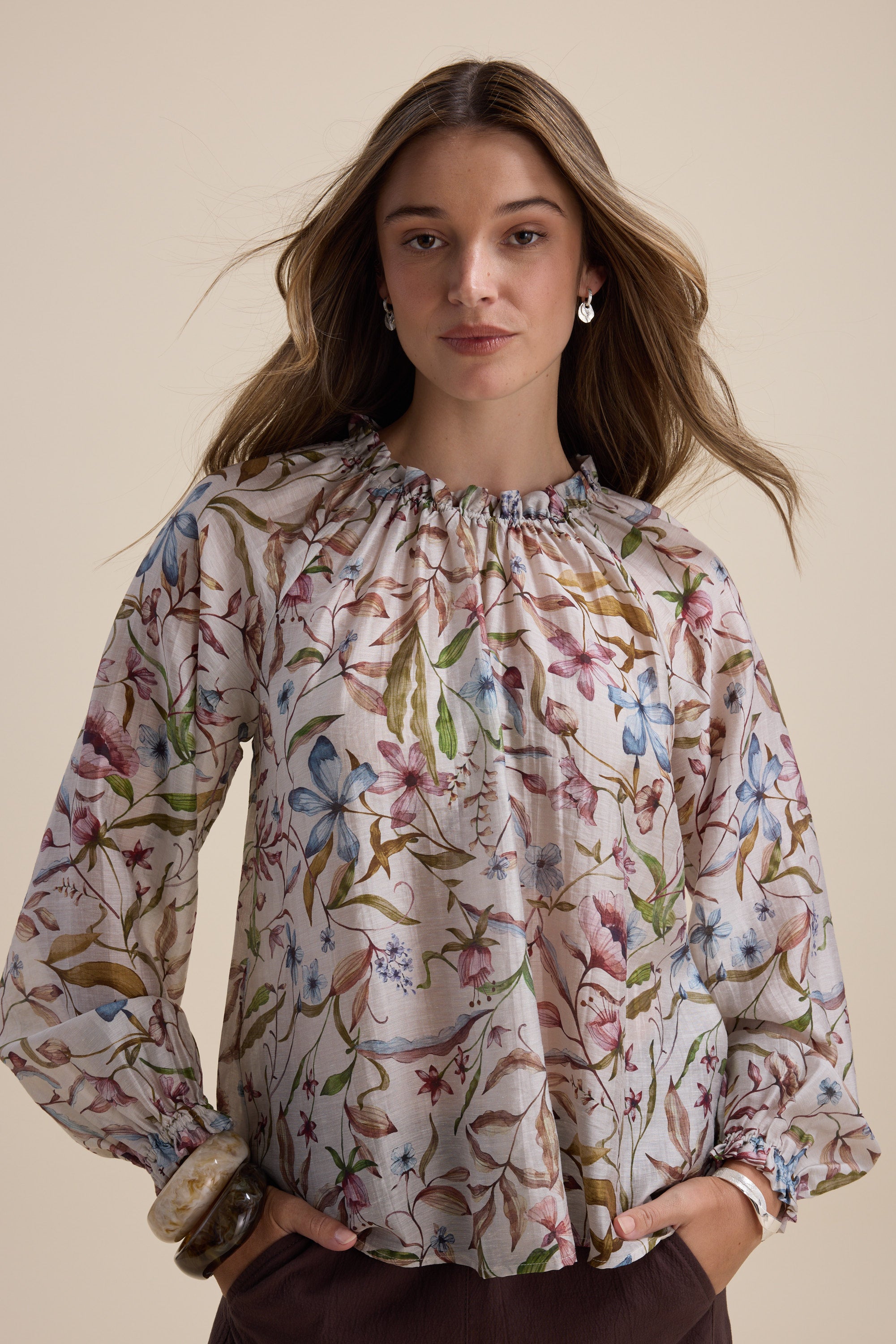Woman in Max Quinn Gather Detail Blouse with long puff sleeves, against a beige background.