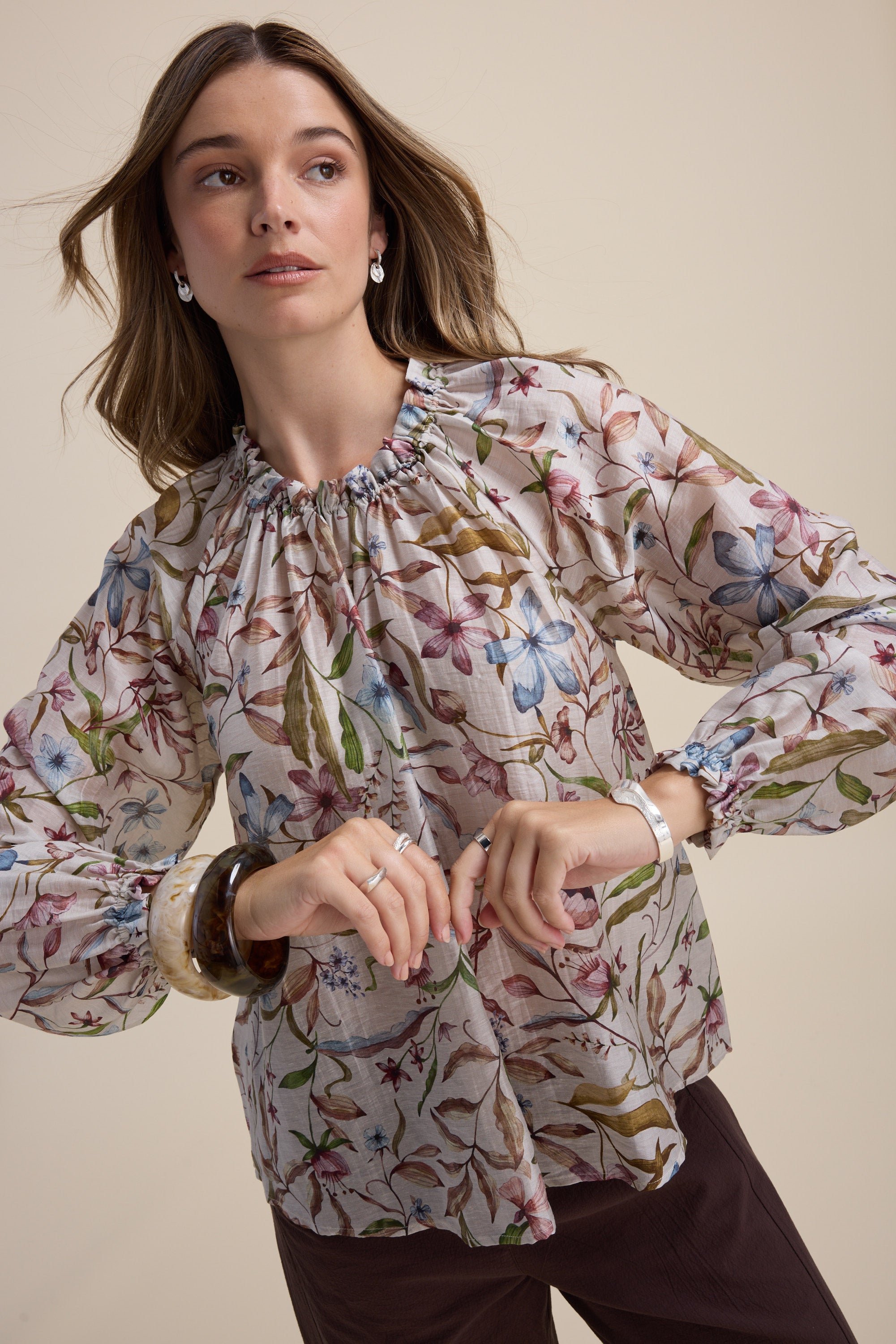 Woman in Max Quinn Gather Detail Blouse and brown pants against a beige background.