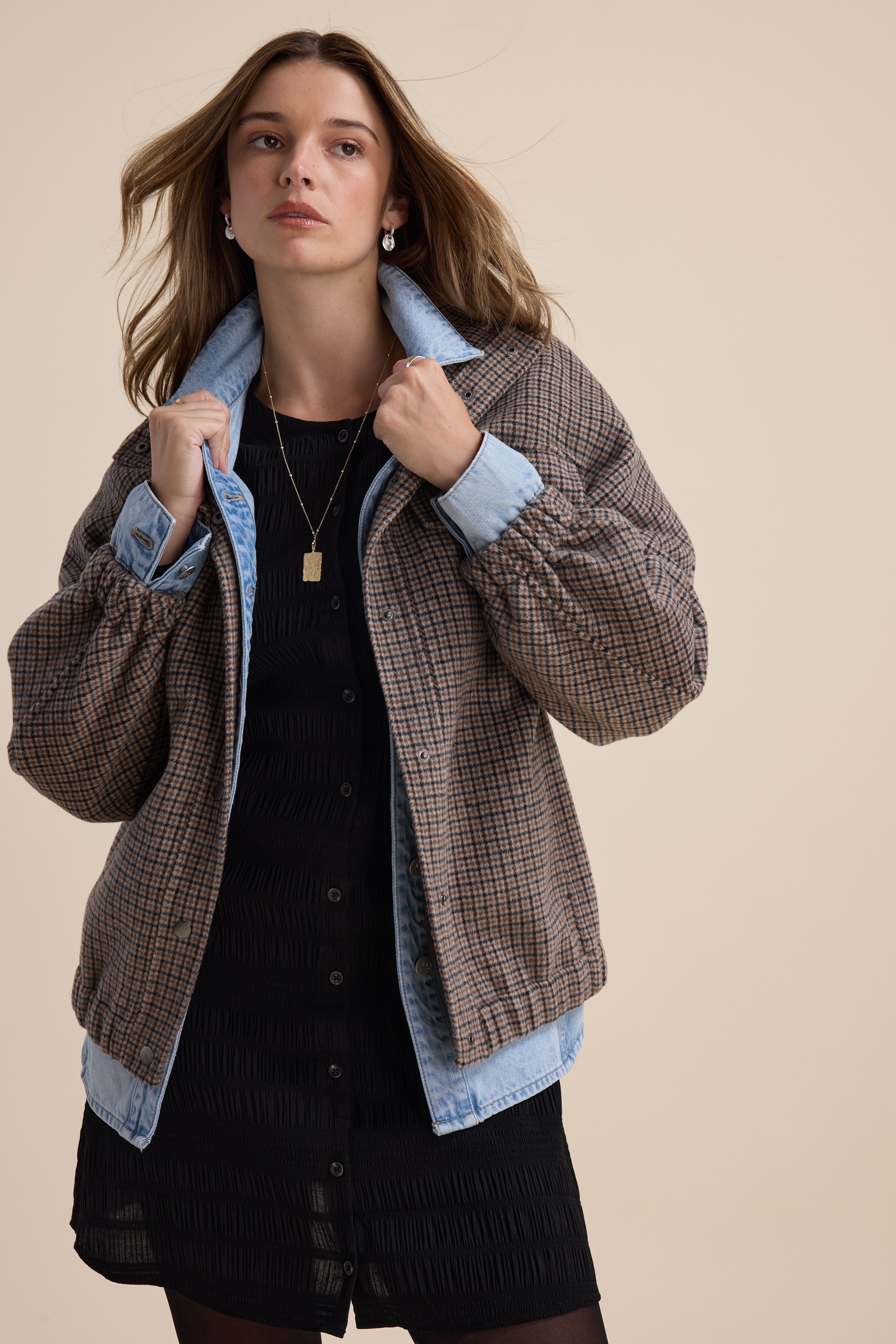 Woman in Tessa Textured Button Front Dress by Max, layered with a checked jacket, beige backdrop.
