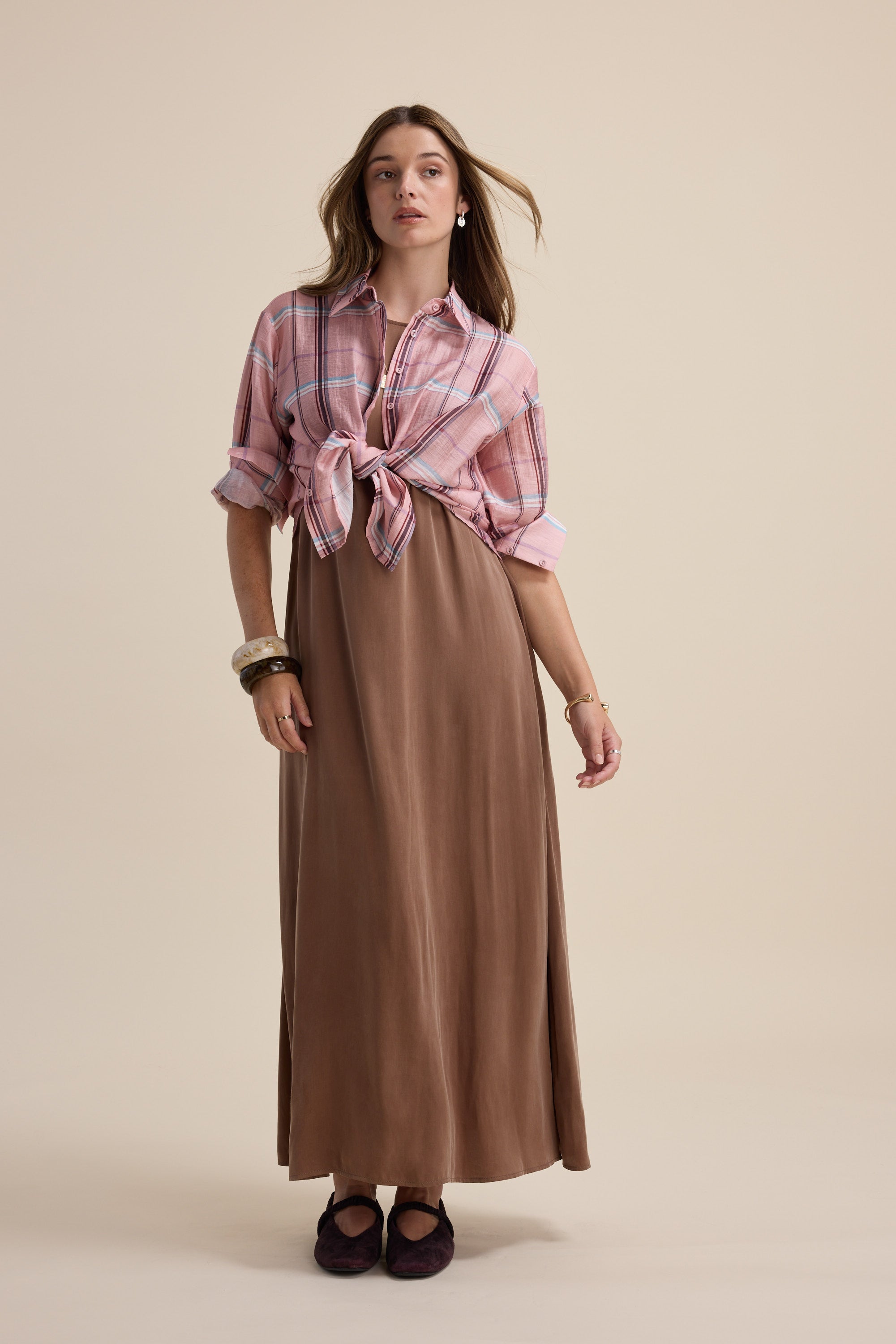 Woman in Max Kaitlyn Flared Midi Dress with a pink plaid shirt tied at the waist.