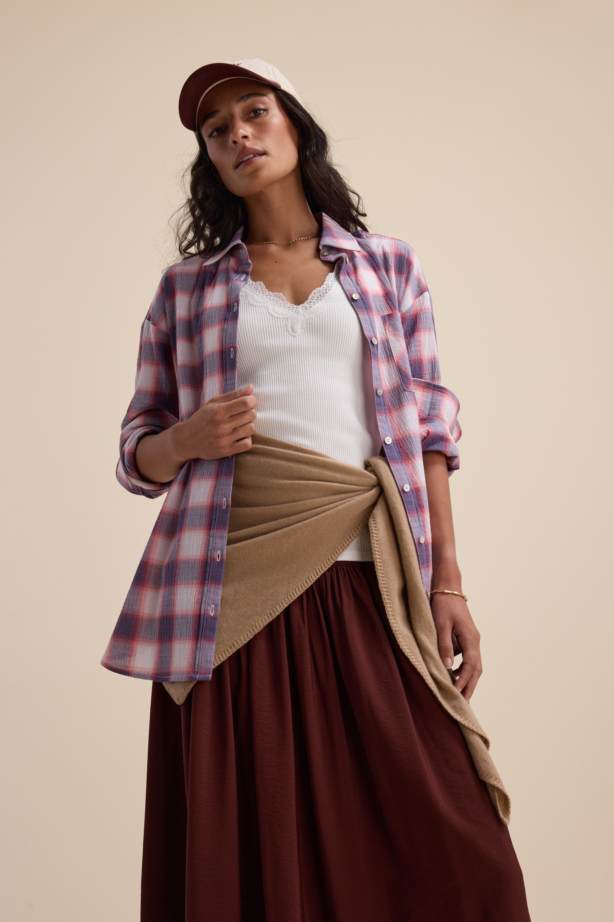 Woman in Elementary Textured Shirt, white top, brown skirt, tan sweater, and pink cap.