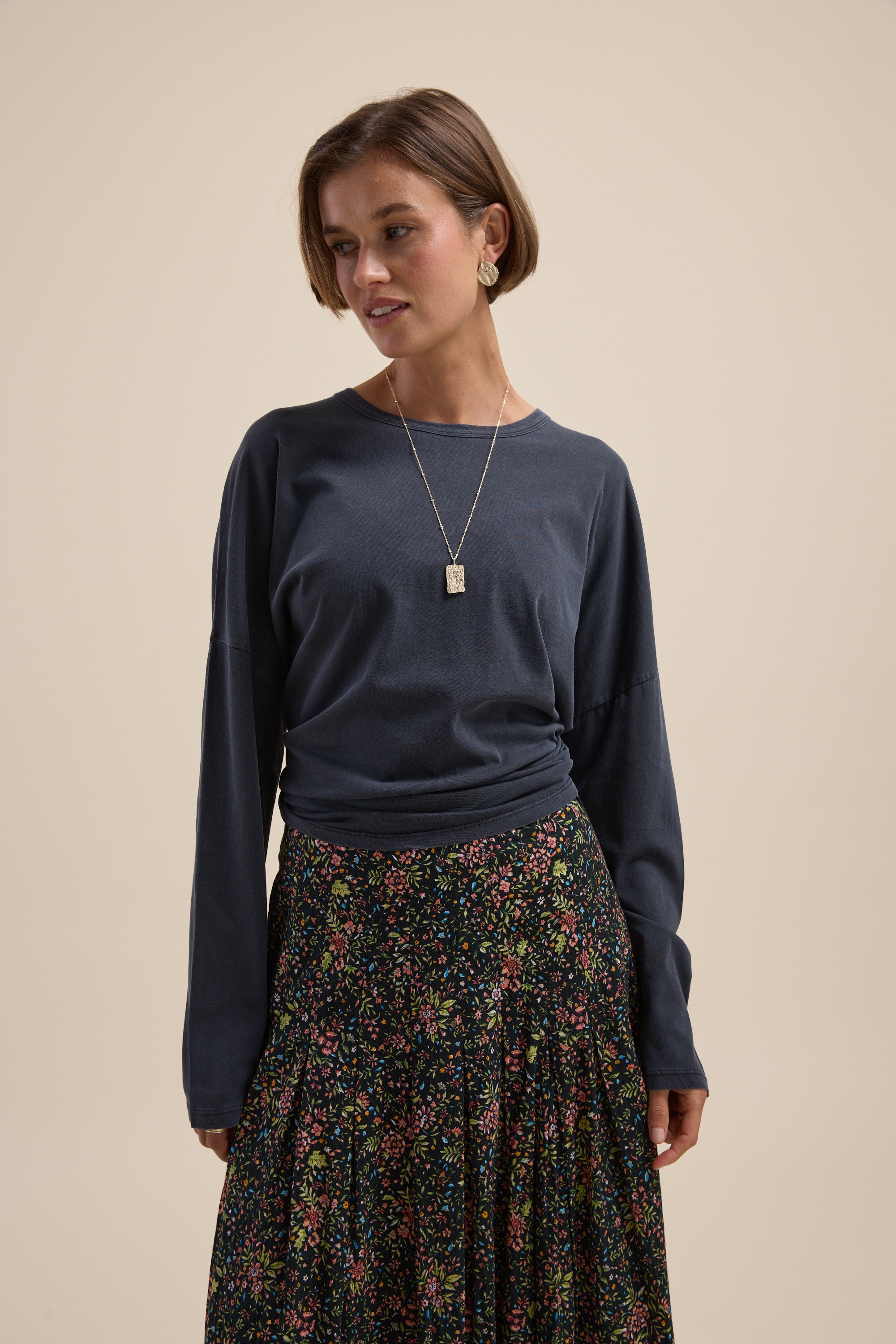 Woman in the Max Elementary Slouchy Long Sleeve Tee, floral skirt, and pendant necklace.
