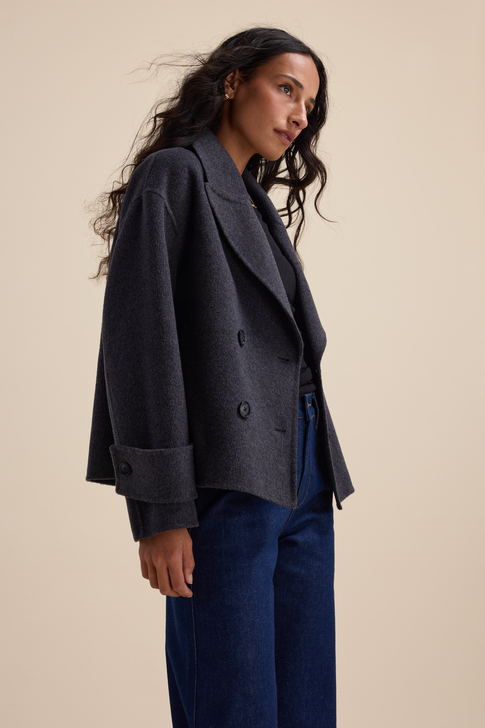 Woman in The Double Breasted Wool Blend Coat by Max and blue jeans, set against beige.