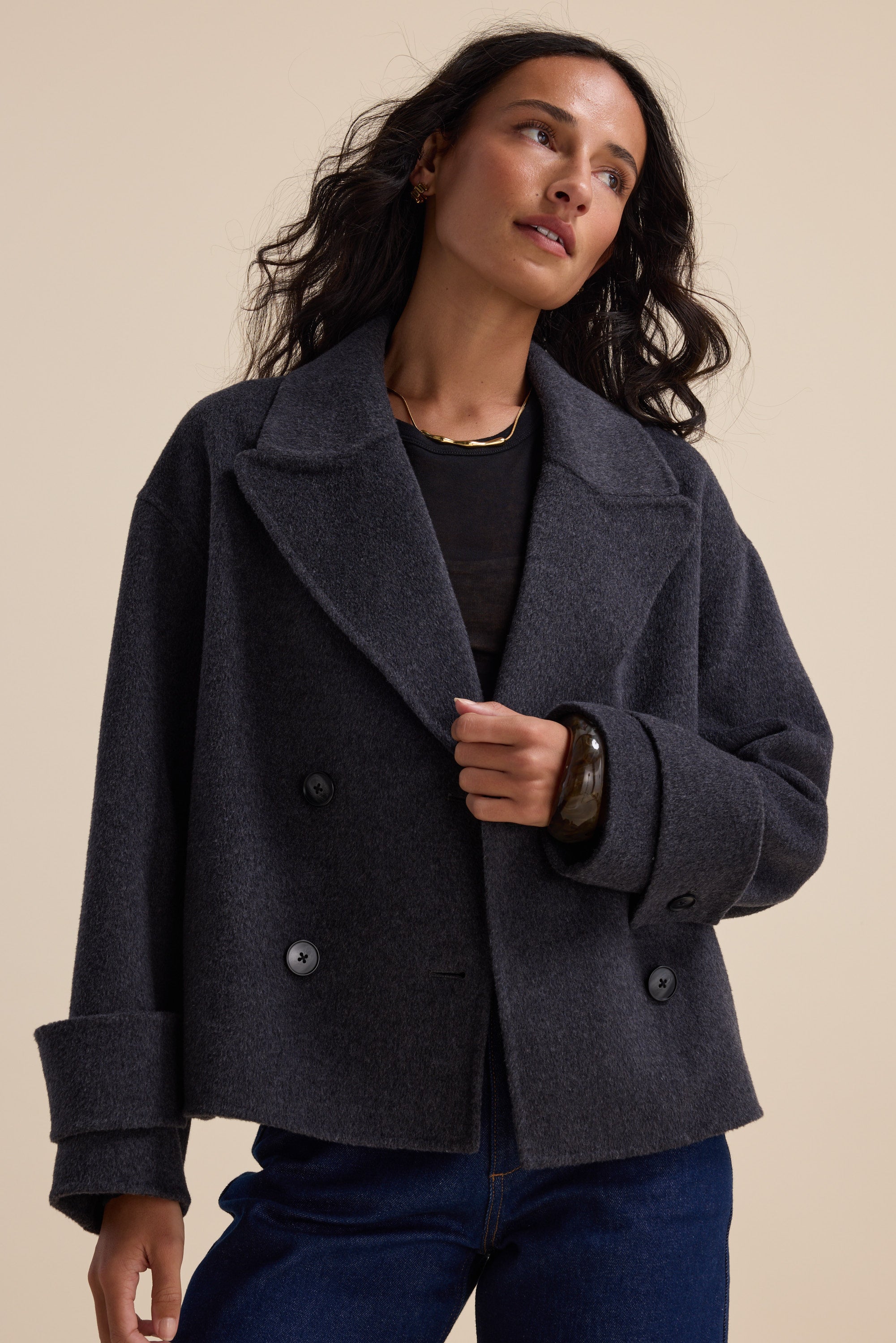 Woman in Max’s Double Breasted Wool Blend Coat and dark jeans against a beige background.