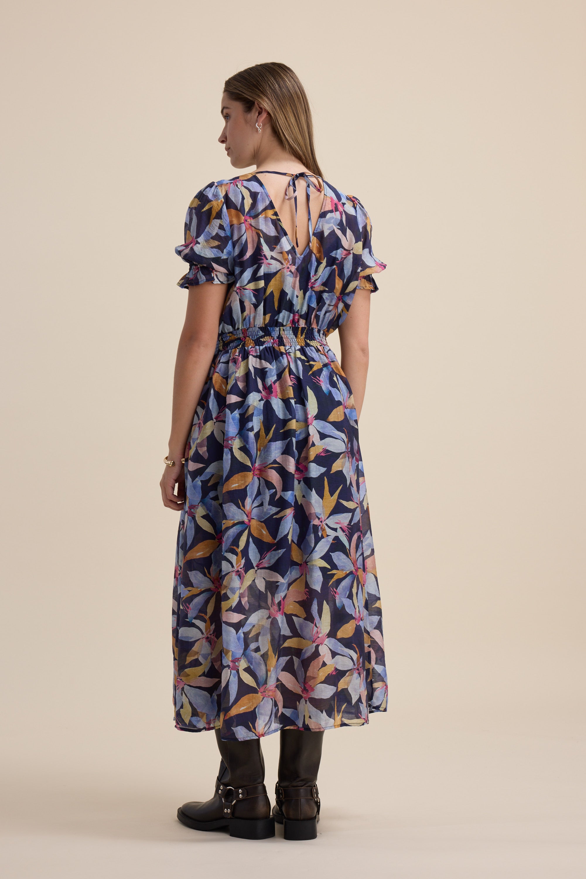 Woman in the Max Ava Gather Waist Dress with puff sleeves, facing away in boots.